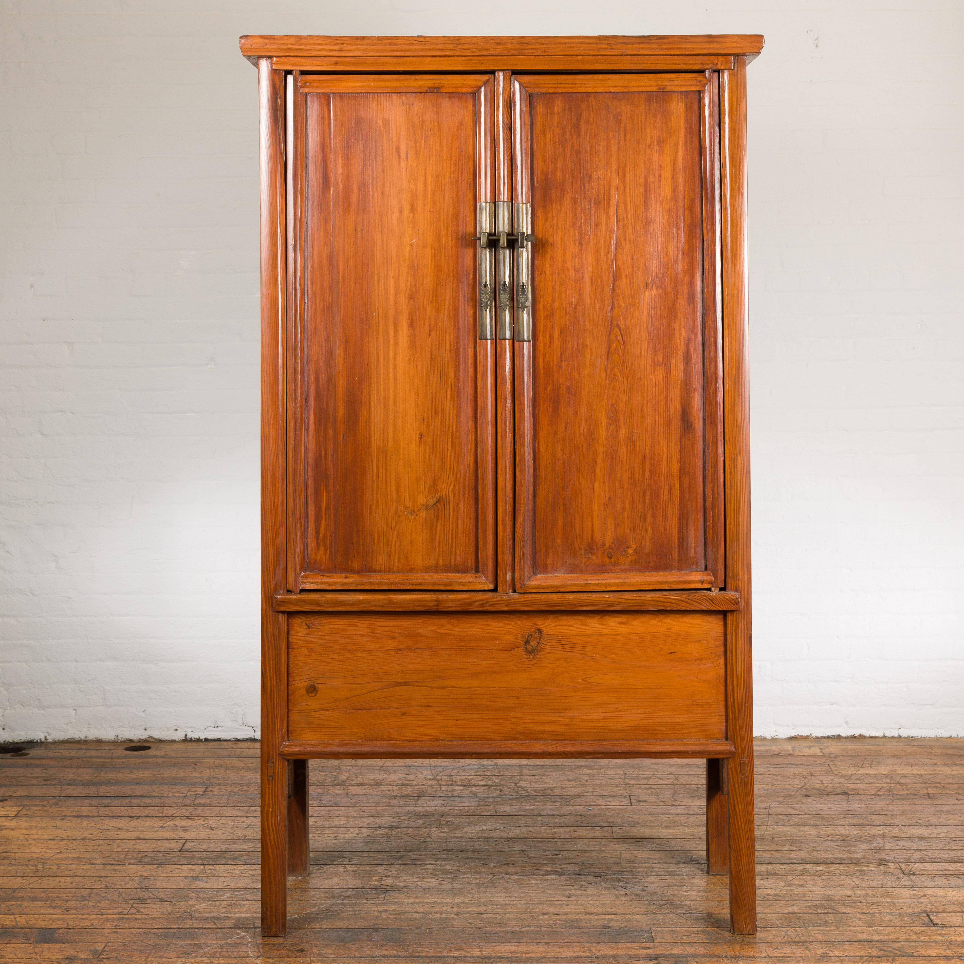 Chinese late Qing Dynasty period noodle cabinet from the early 20th century with two doors, tapered lines, brass hardware, lateral carved aprons, hidden drawers on the inside as well as a removable panel. Emanating an aura of timeless elegance and