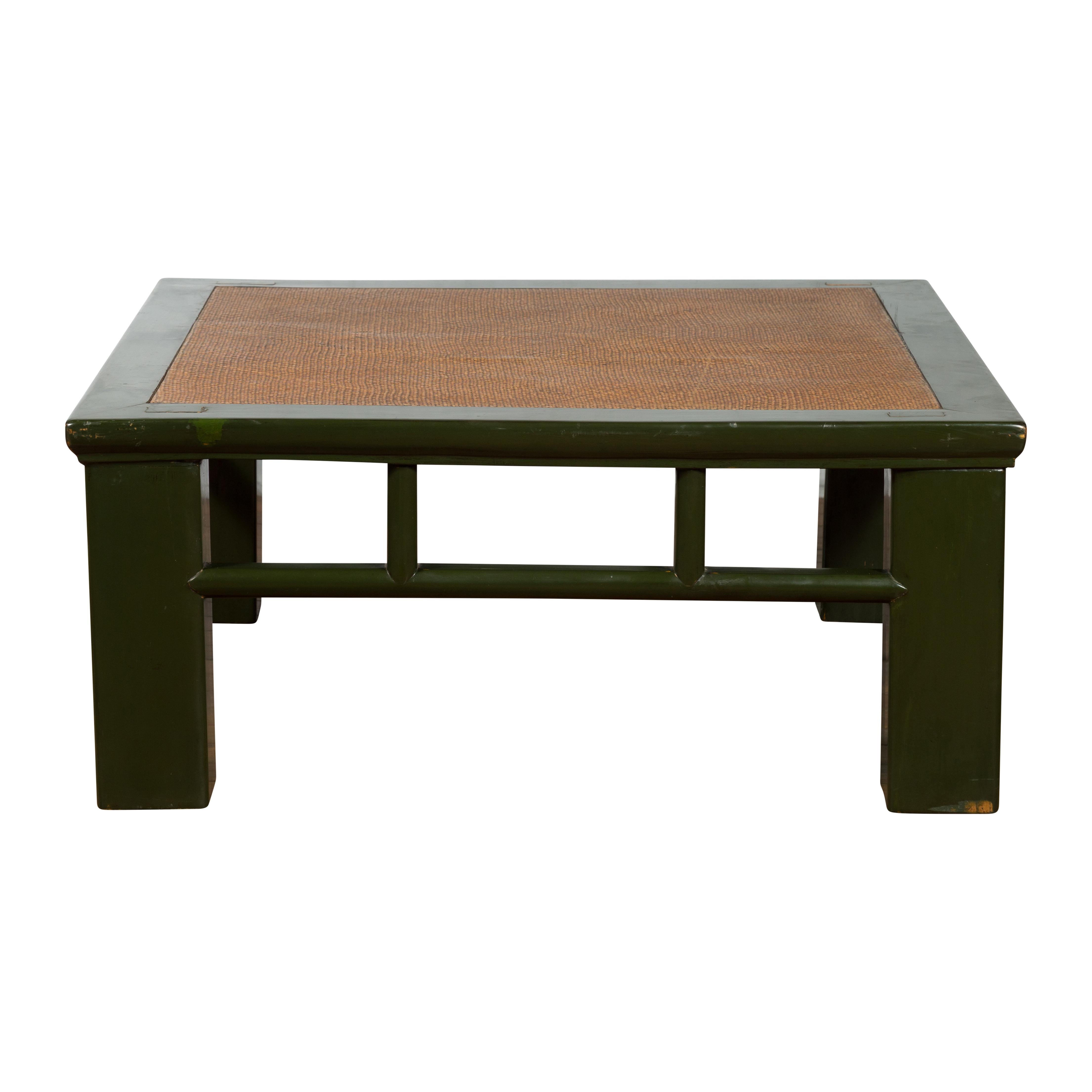 An antique Chinese late Qing Dynasty period wooden coffee table from the early 20th century, with green lacquer, hand-woven rattan top inset, square legs, open apron and pillar strut motifs. Created in China, this low table was originally made from