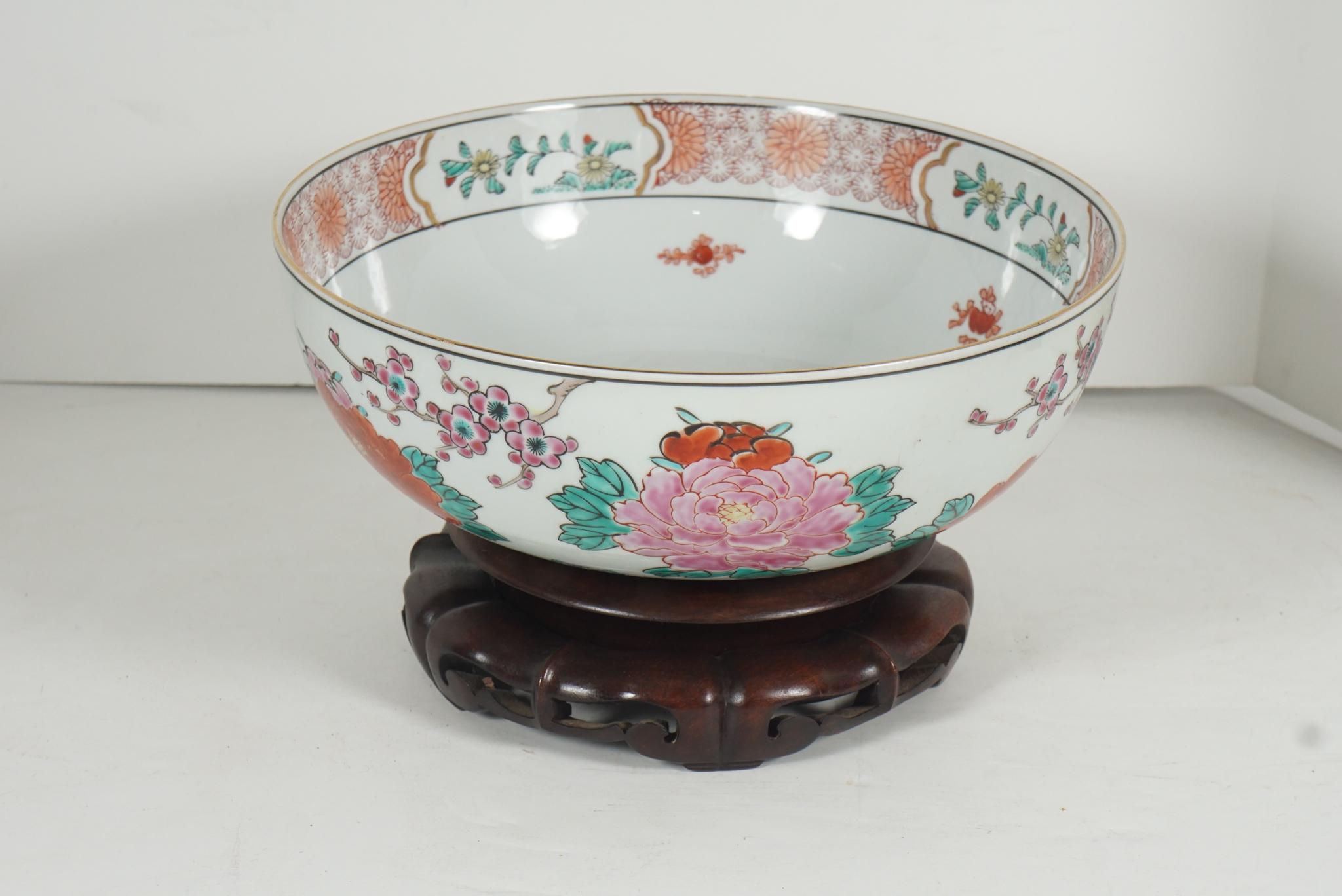 This nice medium-sized bowl has underglaze and overglaze painted details and was made circa 1945 to 1950. It is decorated in an asymmetrical pattern of prunus and chrysanthemums with one pheonix resting on a branch. The inside is decorated at the