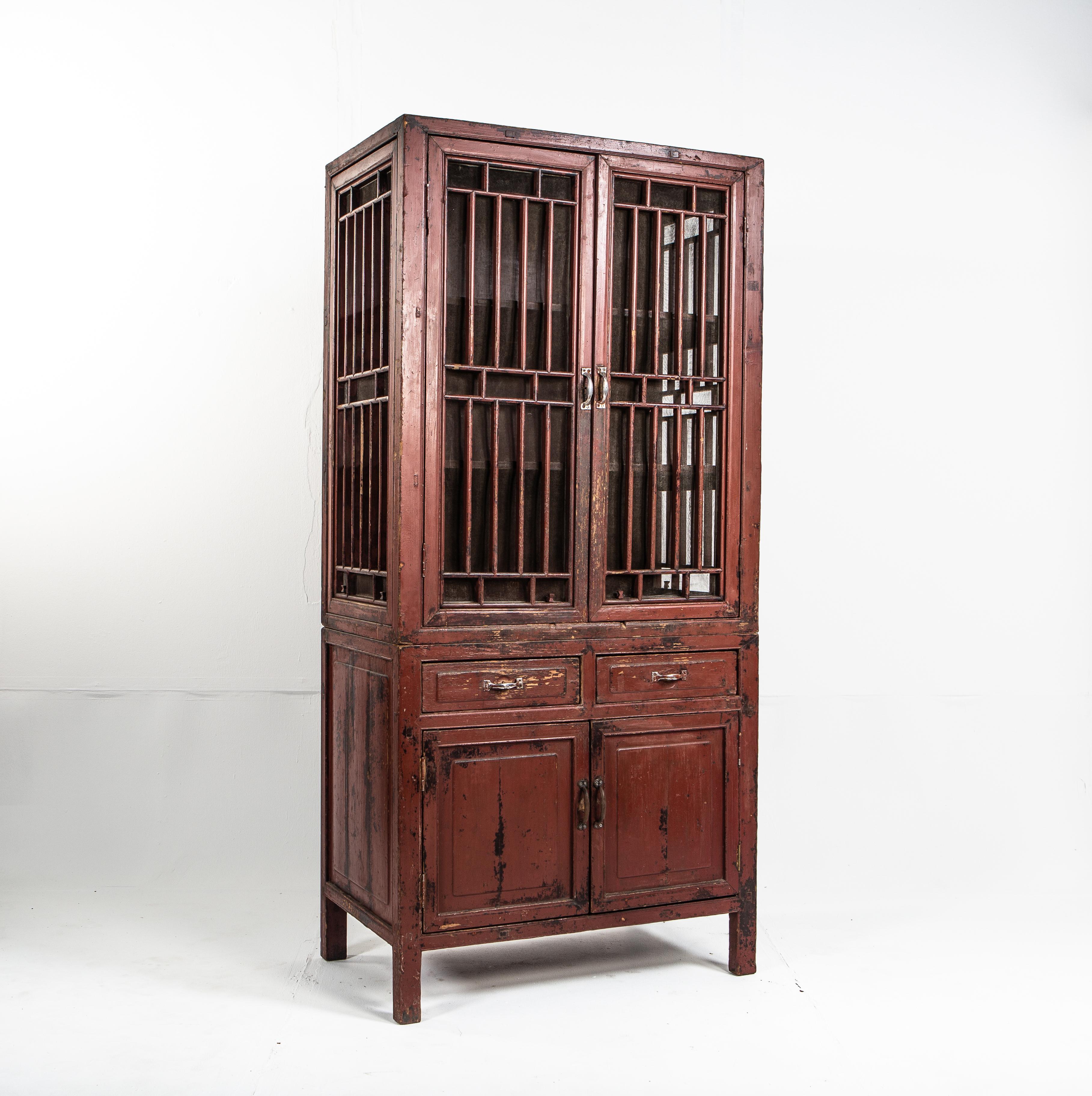 This lattice door cabinet came from Jiangsu, China and dates to the late 1900s. It was originally used to provide extra storage in the dining or sleeping areas of a home. It is made from Fir wood, covered in cinnabar lacquer. Cinnabar is one of the