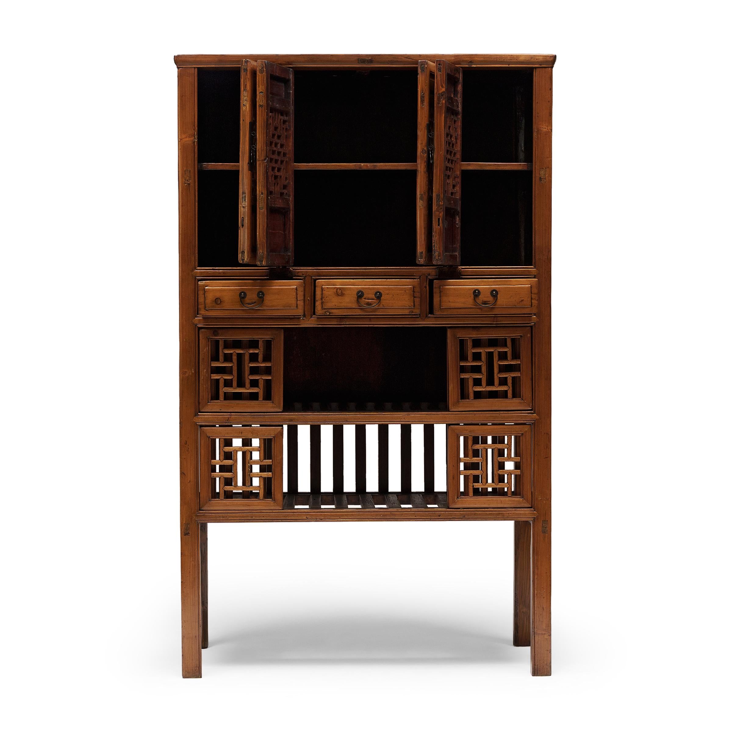 This provincial lattice cabinet from the early 20th century was once used in a rural Chinese kitchen to store dishware, baskets and other kitchen supplies. Crafted of cypress with traditional mortise-and-tenon joinery, the tall cabinet has a