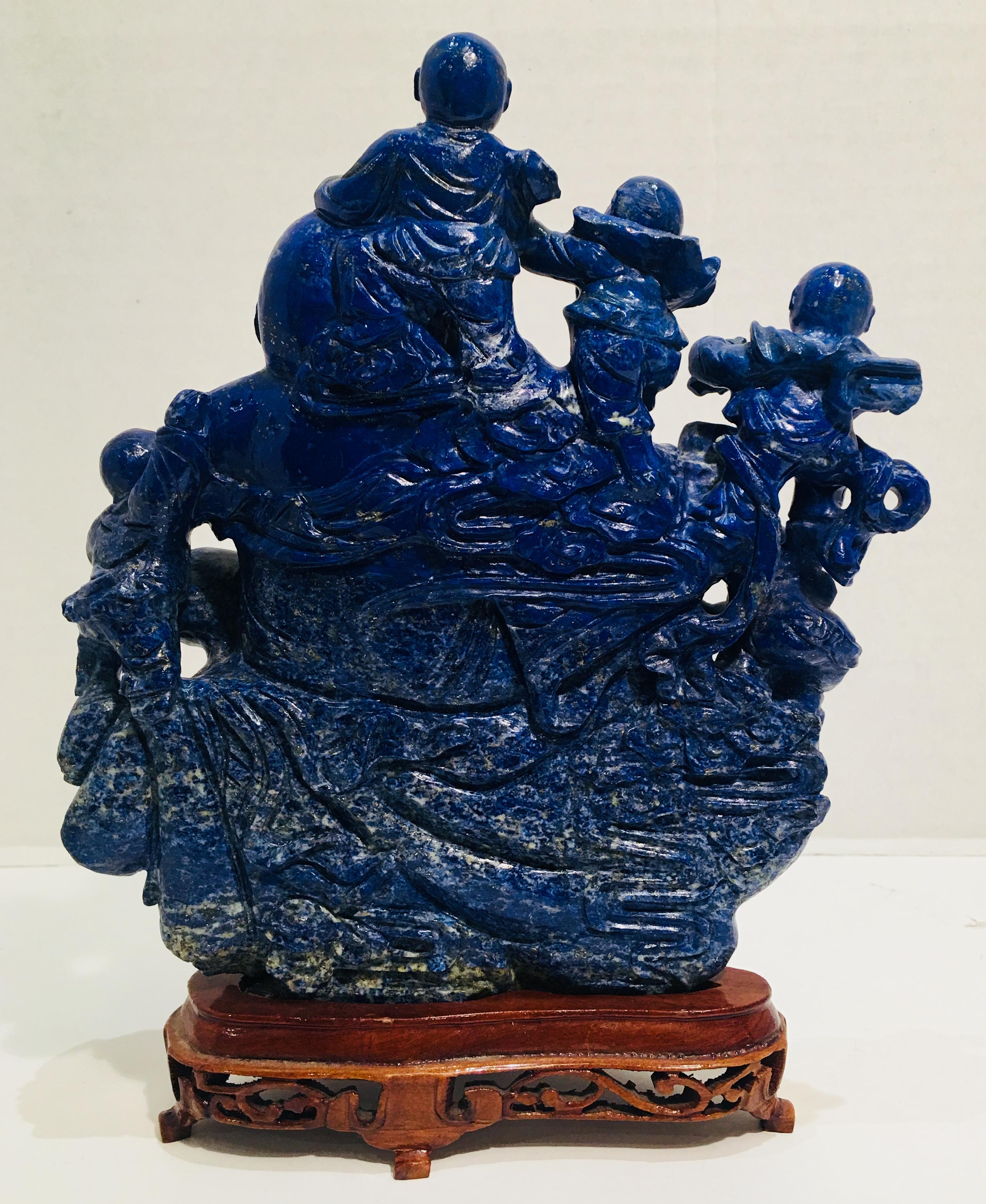 Carved lapis lazuli statue of Chinese Laughing Buddha and his five children with a removable carved wooden Stand is a vintage, estate, three-dimensional, intricately hand-carved, bright blue, variegated lapis lazuli stone sculpture.

Known by