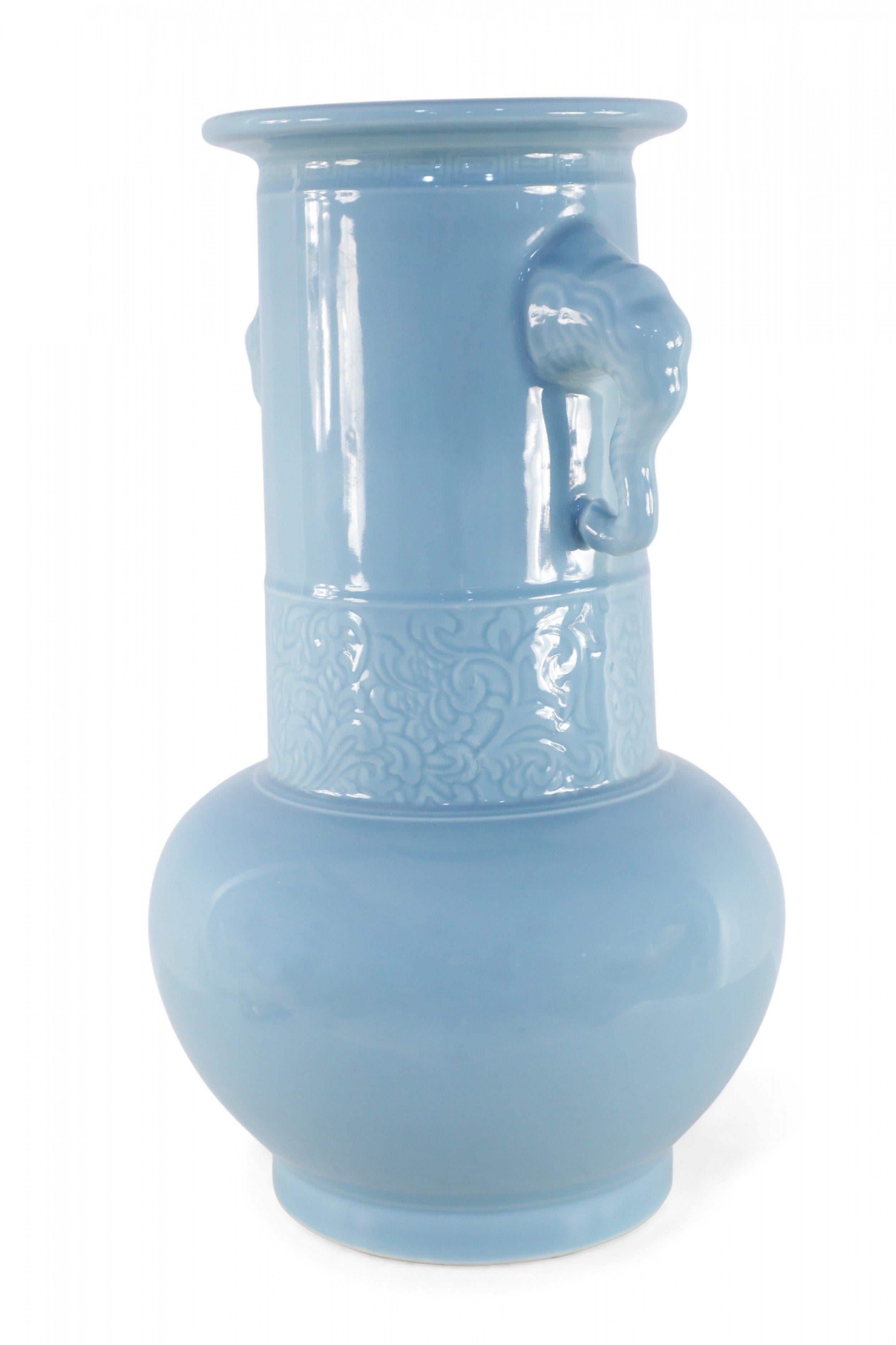 Chinese light blue porcelain vase with a tonal floral band below double elephant-shaped handles on the neck.
 