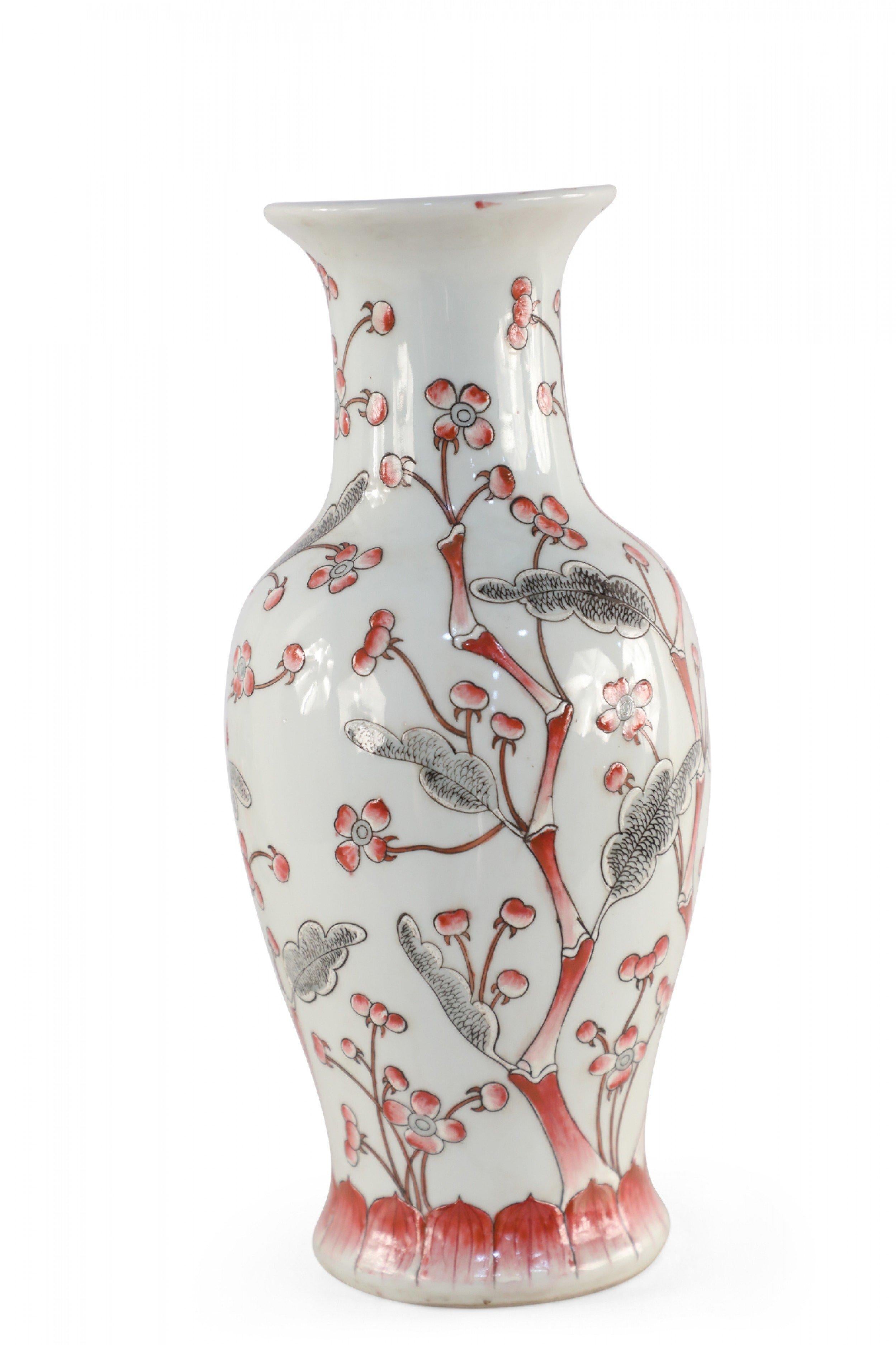 Chinese light gray porcelain vase with a flowering red and gray cherry blossom tree stretching up its urn-shaped form.
  