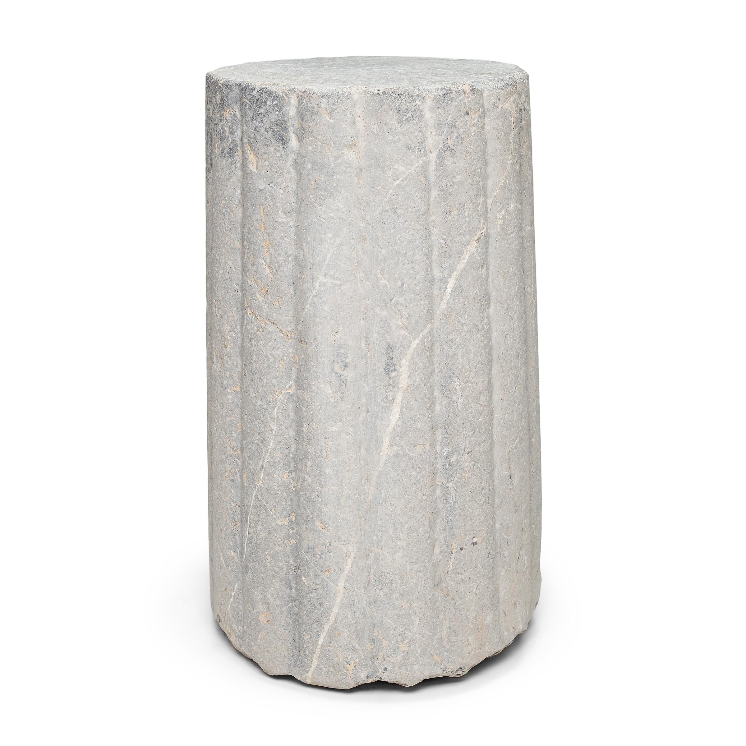 This unusual stone pedestal is actually a late 19th-century cylindrical mill stone. Hand-carved of solid limestone with a textured and ribbed surface, the stone was used for threshing wheat and other grains on a farm in China's Shanxi province. The