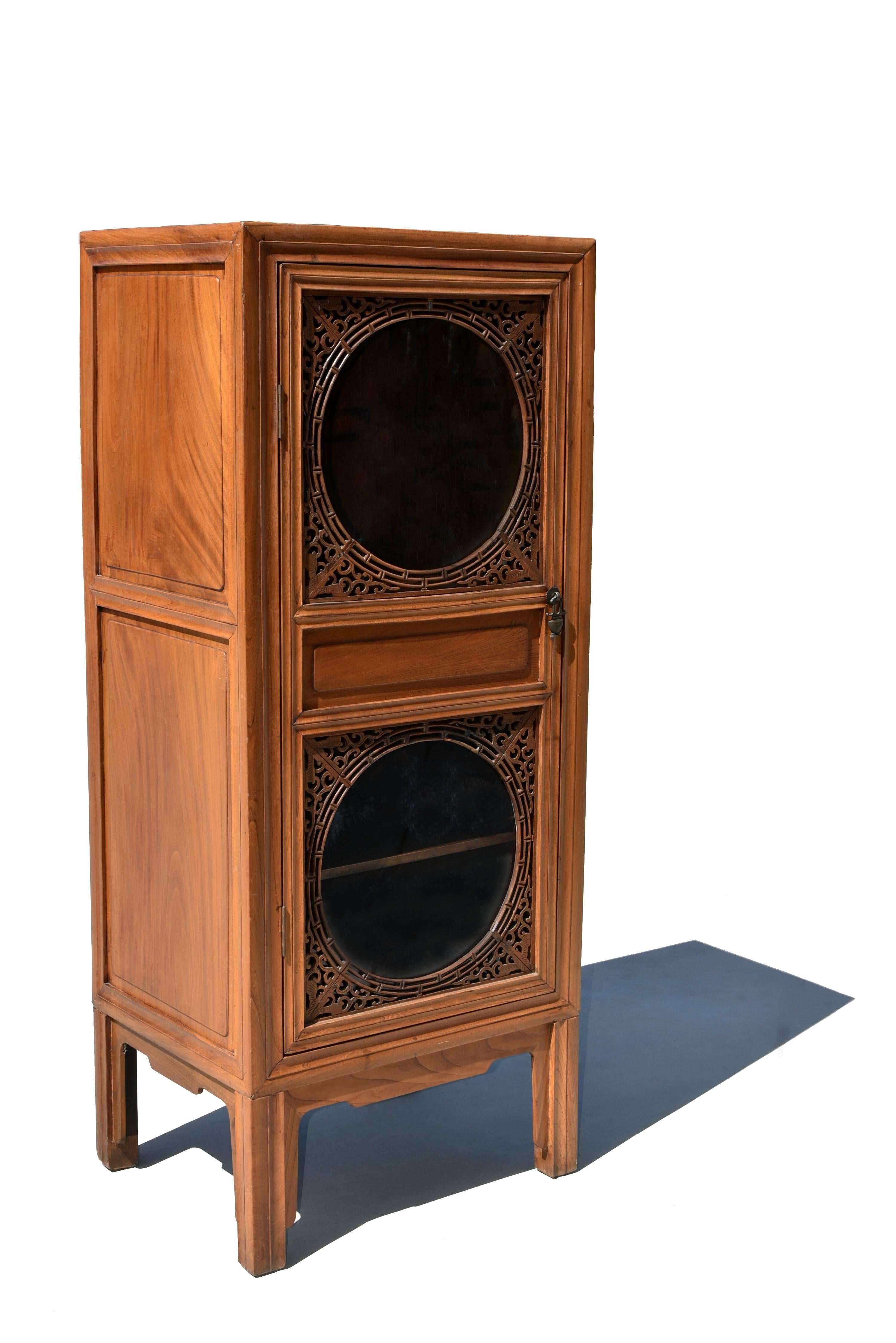 A beautiful 20th century solid wood custom linen press with glass door. The cabinet is constructed with three frame members, among them two are inset with choice elm woods that form the sides. The elm woods with grains of swirls and sweeps resemble