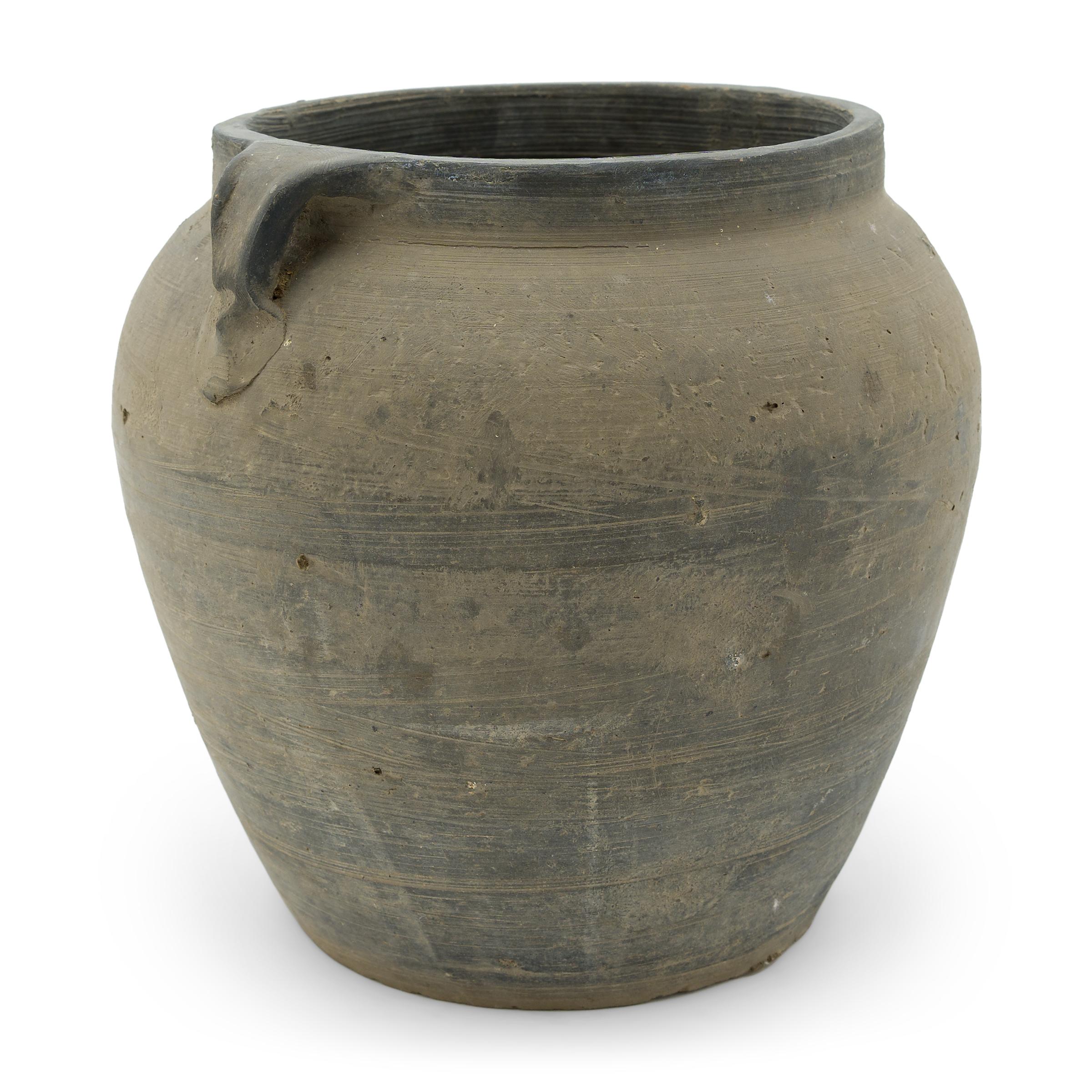 Charged with the humble task of storing dry goods, this small earthenware jar is hand-shaped with balanced proportions and a beautifully irregular unglazed surface. The round jar has a gently tapered form with a narrowed neck and high shoulders
