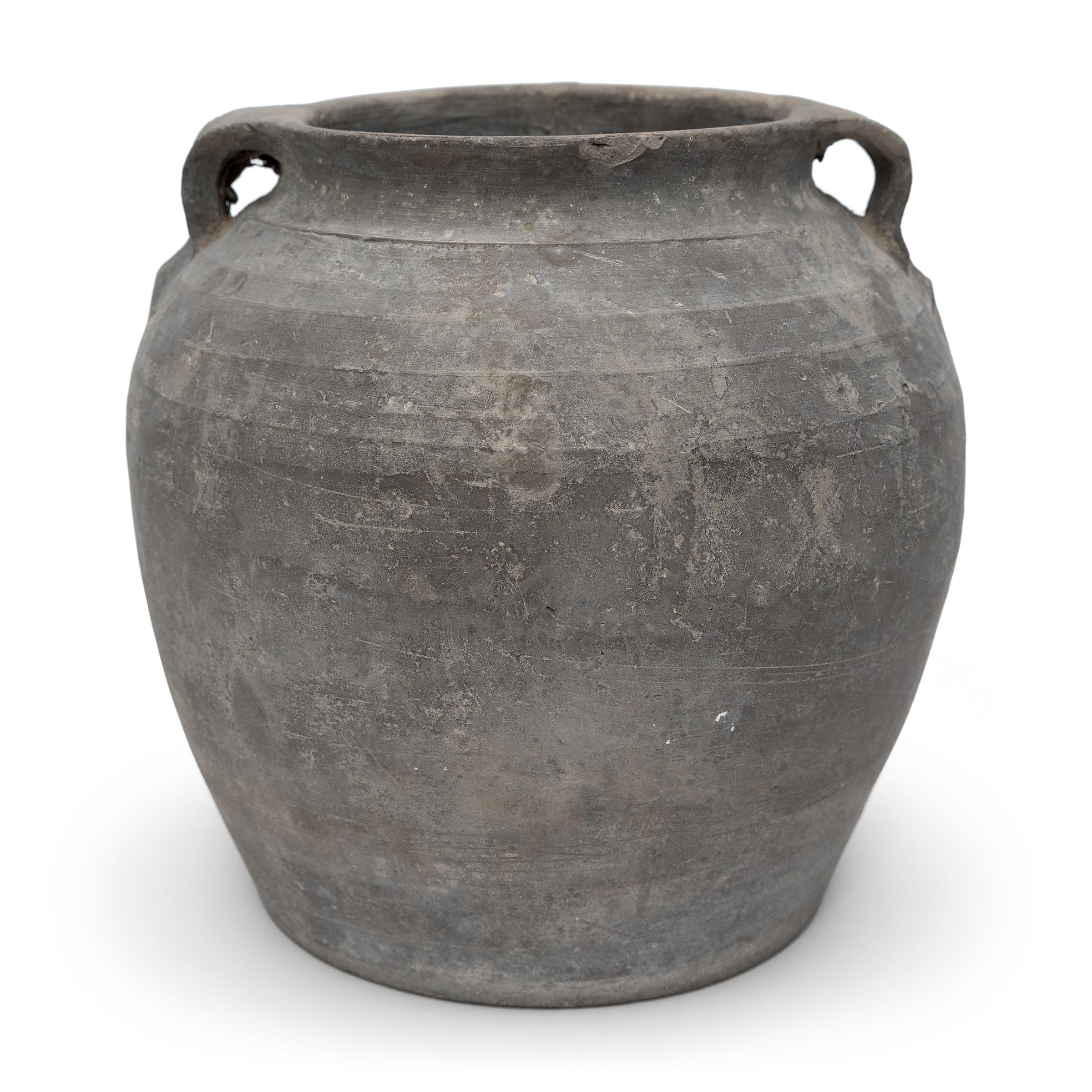 Charged with the humble task of storing dry goods, this small earthenware jar is hand-shaped with balanced proportions and a beautifully irregular unglazed surface. The round jar has a gently tapered form with a narrowed neck and high shoulders