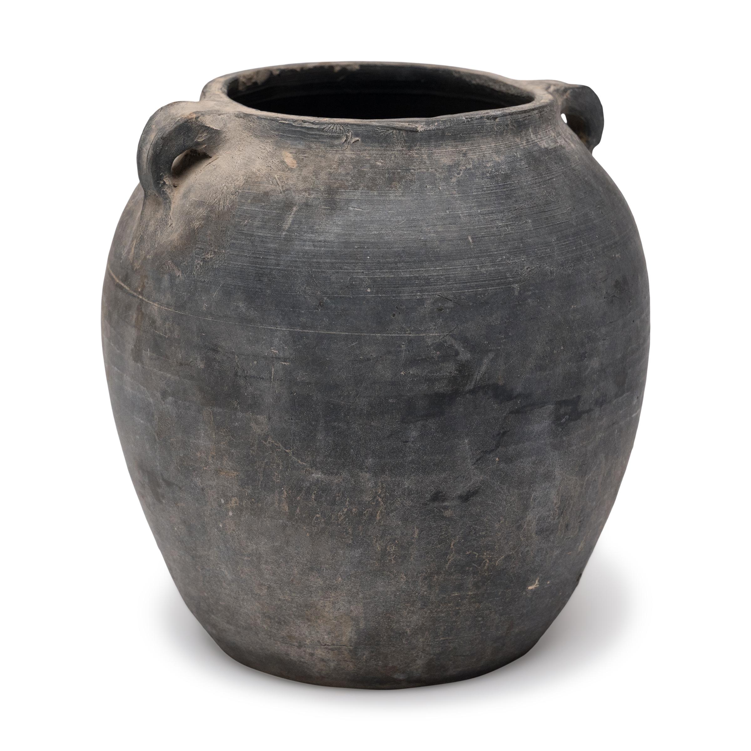 Charged with the humble task of storing dry goods, this small earthenware jar is hand-shaped with balanced proportions and a beautifully irregular unglazed surface. The round jar has a gently tapered form with a narrowed neck and high shoulders