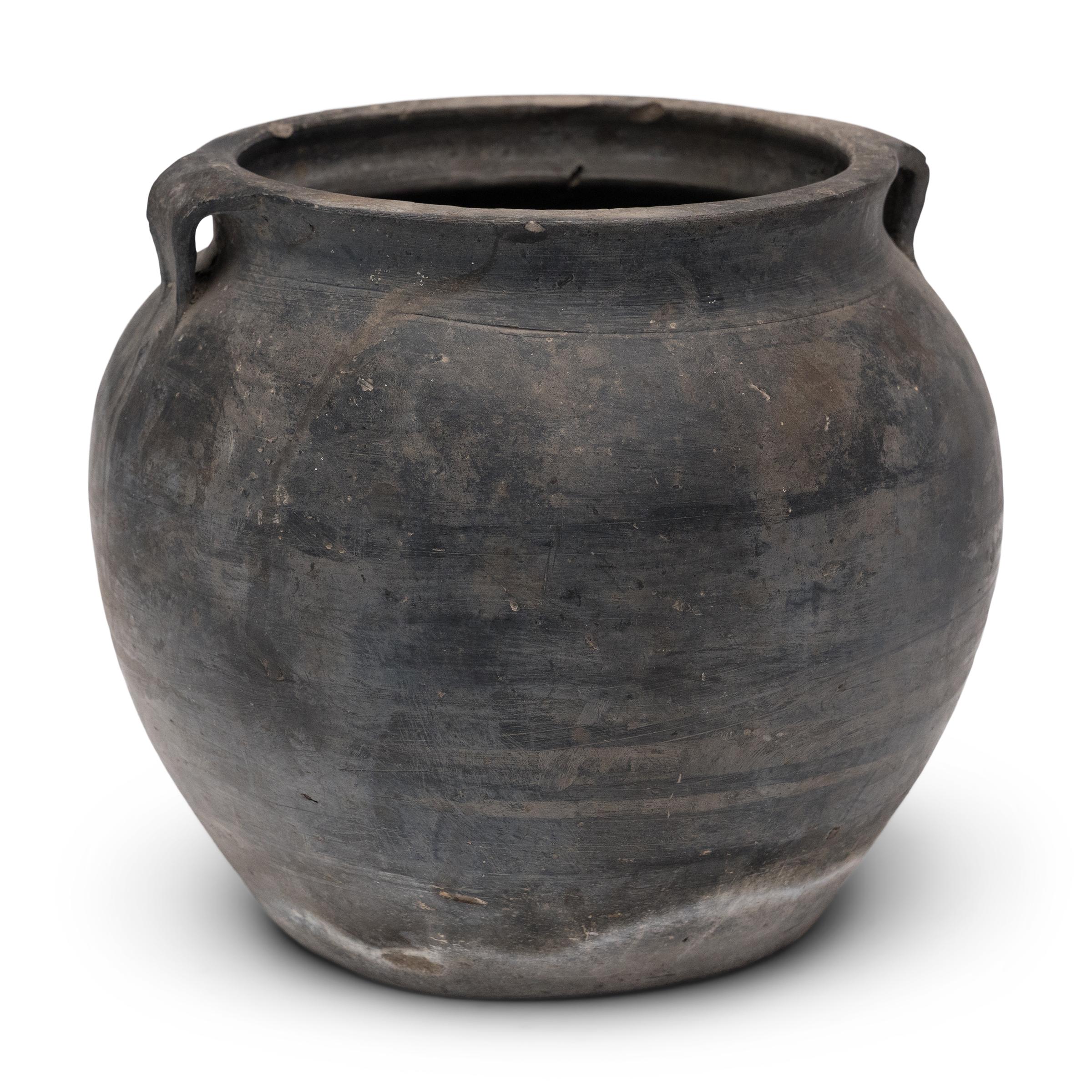 Chargée de l'humble tâche de stocker des produits secs, cette petite jarre en terre cuite est façonnée à la main avec des proportions équilibrées et une surface non émaillée magnifiquement irrégulière. La jarre ronde a une forme légèrement effilée