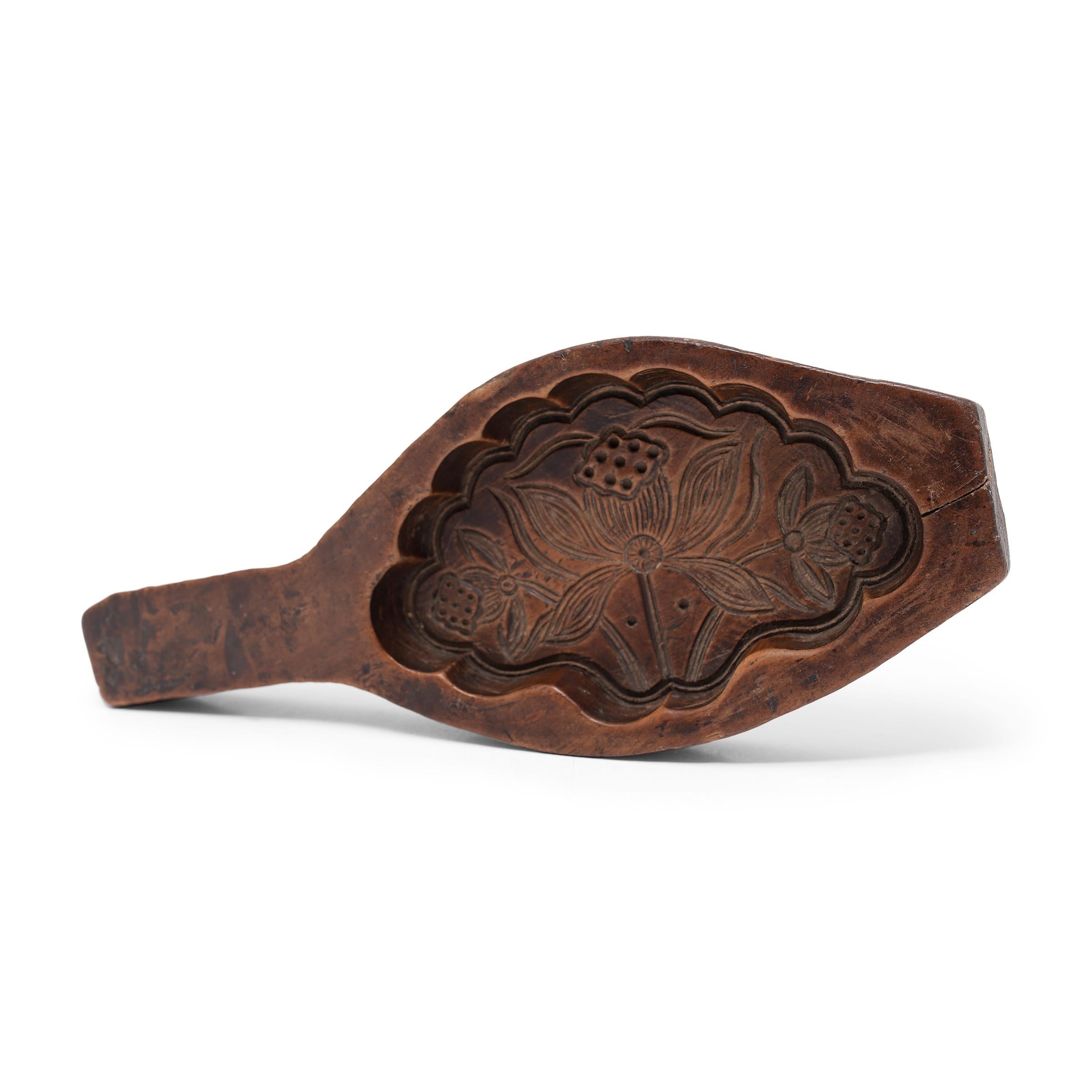 This 19th-century hand-held wood press is carved with a large mold used for shaping festive mooncakes. Packed with lotus root, red bean, or other regional fillings, mooncakes are a delicacy eaten during the Mid-Autumn Festival as an offering between