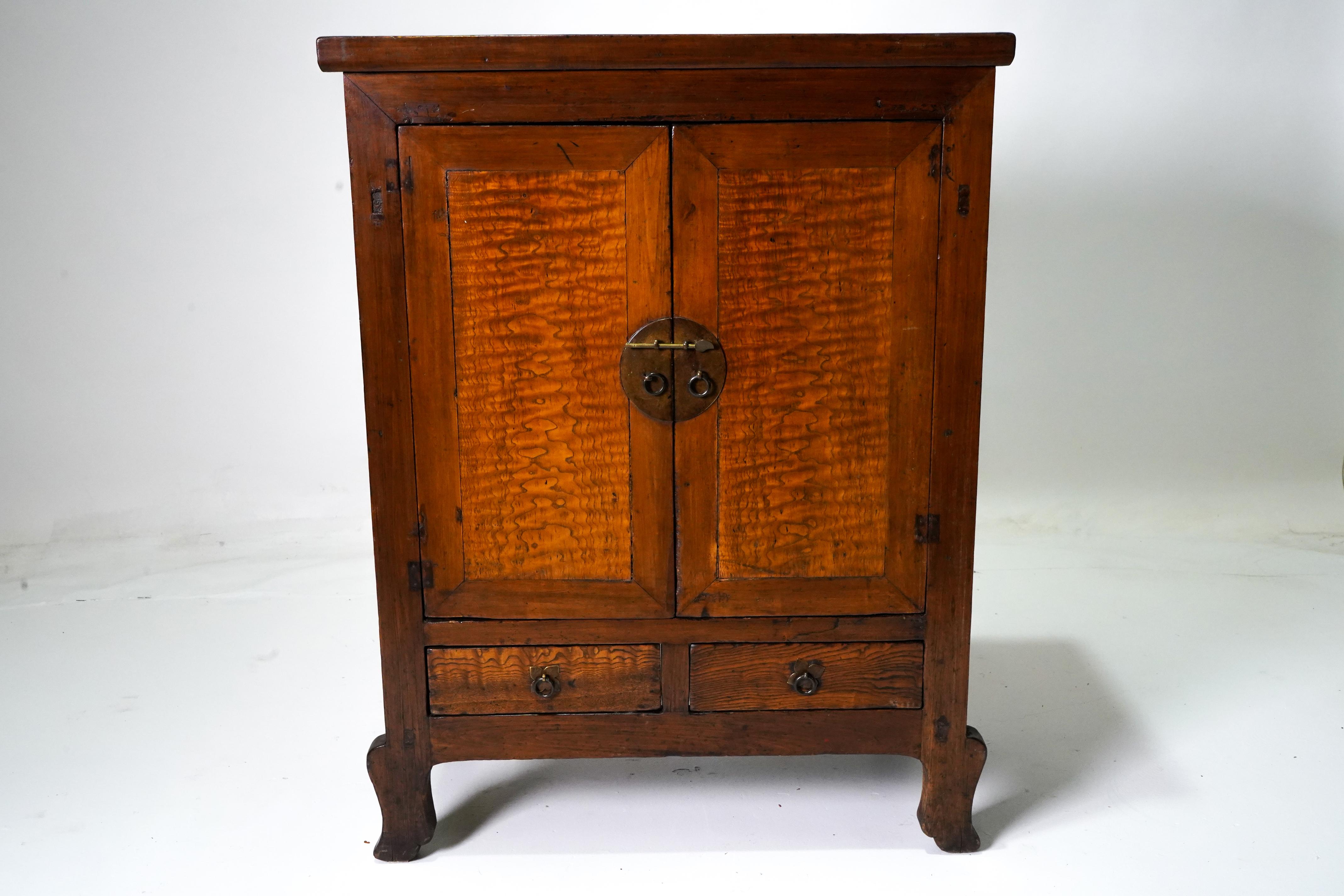 This elegantly-scaled cabinet was used to hold blankets and personal effects in a Northern Chinese home. The simple, unbeveled frame is enhanced with cabriole legs, doors with beautiful burled-wood center panels and a round brass lock plate. The