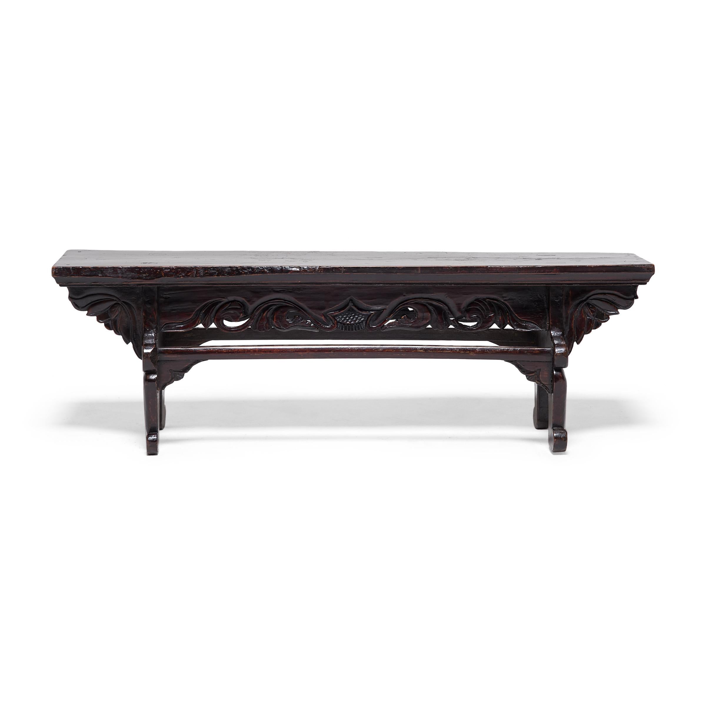 Dieser niedrige Tisch aus dem 19. Jahrhundert ist eigentlich eine Trittstufe, die den Ein- und Ausstieg aus einer erhöhten Liege erleichtert. Die aus nordischem Ulmenholz (Yumu) gefertigte Stufe hat eine Bohlenoberseite, geschnitzte Lotuszwickel und