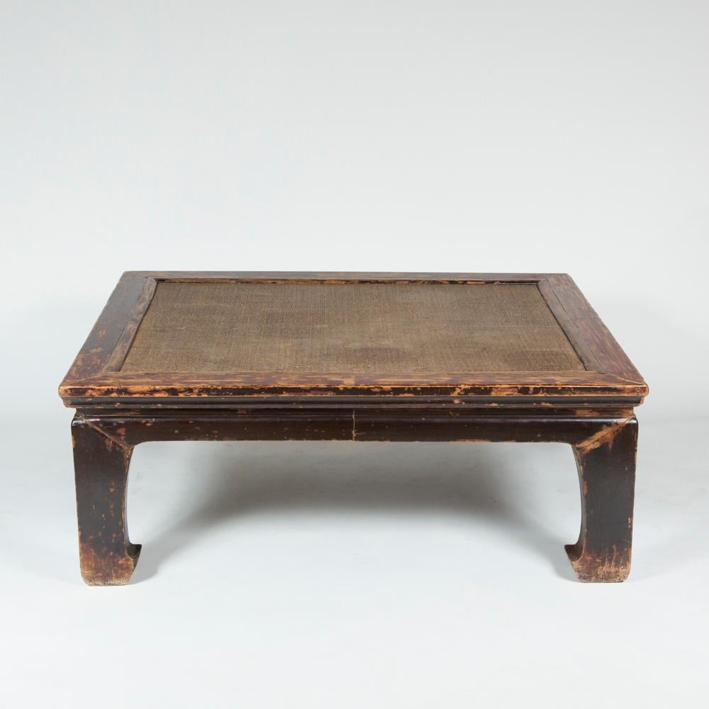 A Chinese painted elm low table with woven rattan inset top and hoof legs.

