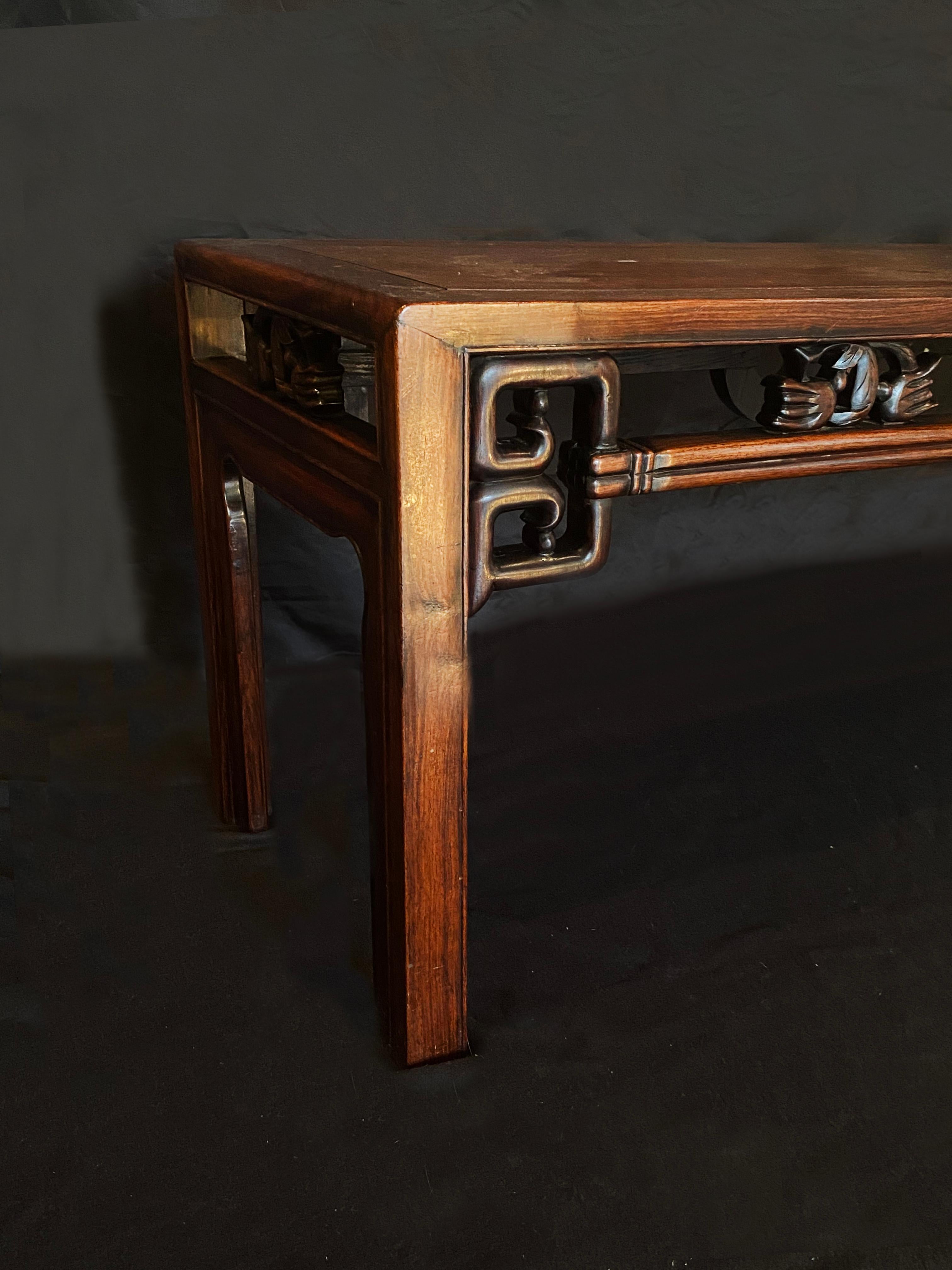 A Chinese mahogany low alter table inspired by Chinese design. An elegantly simple shape with intricate Chinese design details. The frieze has geometric features, as well as stylized flora and birds. A beautiful piece of furniture to add to any