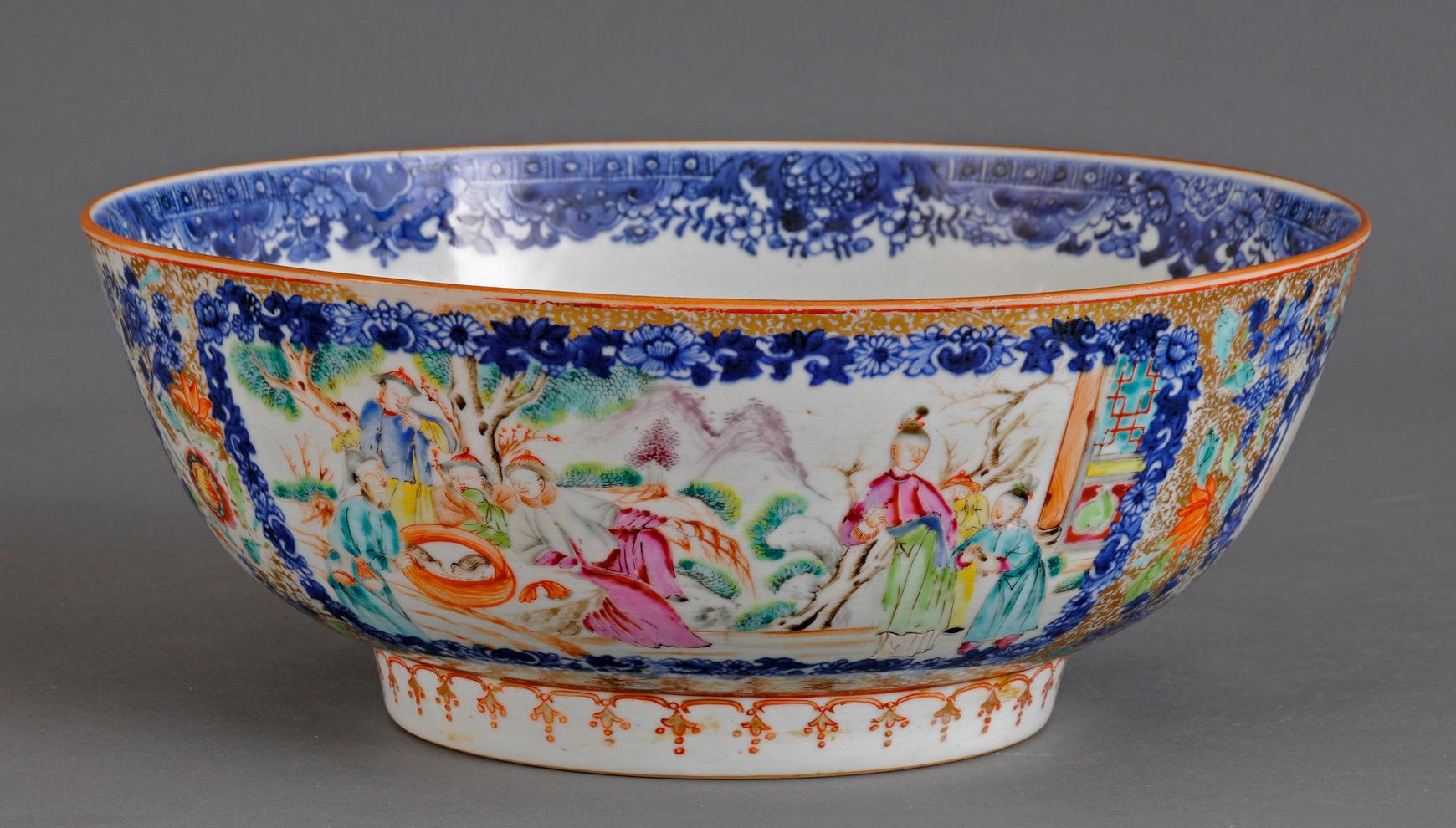 Large Chinese Mandarin porcelain punch bowl with enameled exterior with two panels depicting colorful figures feeding birds in a courtyard along the river. The inside rim is a blue and white border of flowers and foliage. The inside bottom is