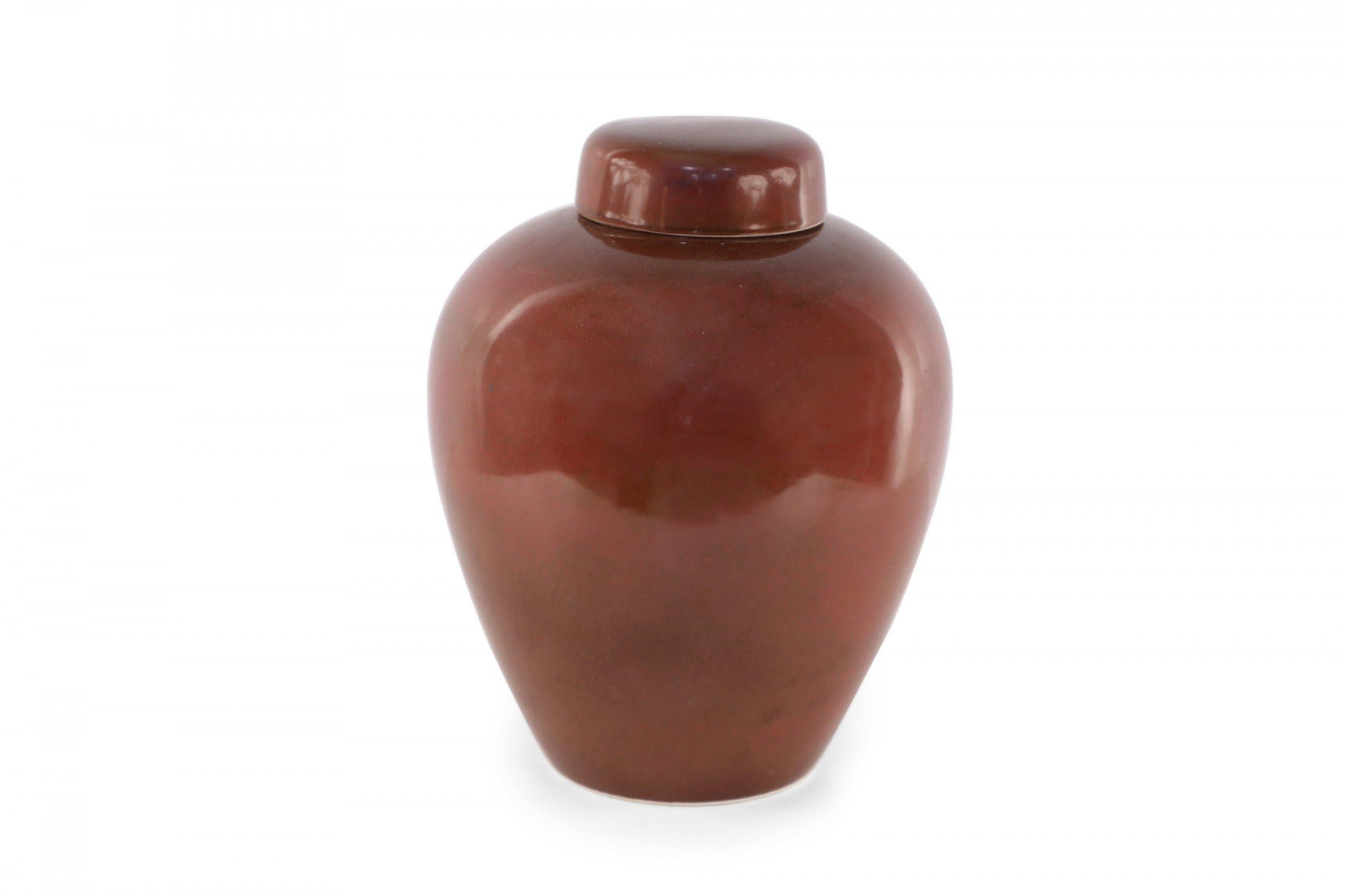 Chinese porcelain lidded ginger jar in a finish that shifts within a range of umber, red and maroon, adding dimension to its shape.
       