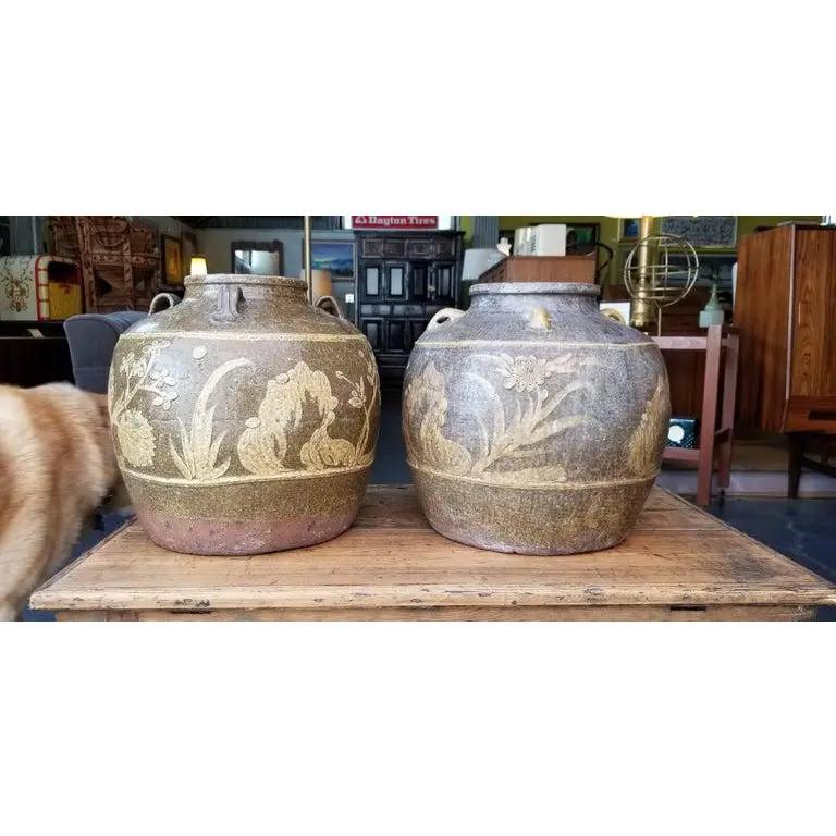 Extraordinary organic texture and earth-tone glaze to this pair of antique, centuries old, Chinese Martaban storage jars. Flora and fauna decoration. These are not a perfectly matched pair. Measurements listed are for each jar.