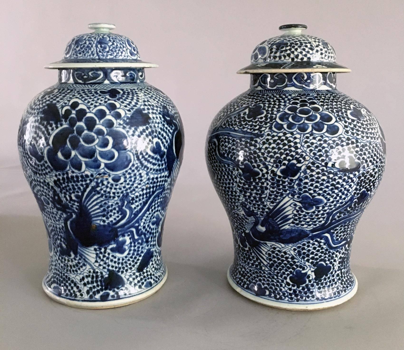 Chinese matched pair of porcelain blue and white vases and covers, decorated with flying phoenix birds on a background of deep cobalt clouds and swirling dots.