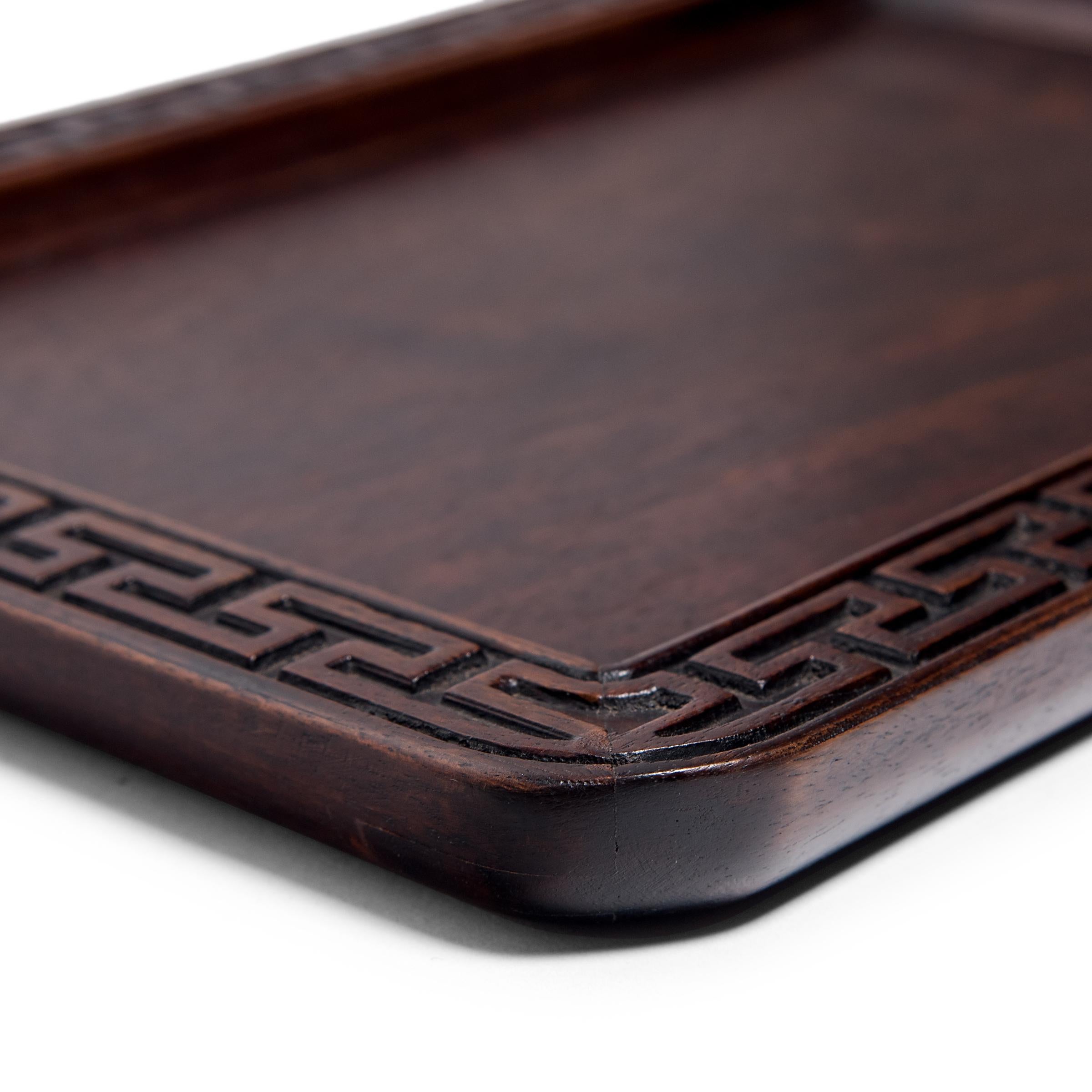 Beautifully carved of a fine-grained hardwood, this late 19th century tray reflects the Qing-dynasty literati's taste for fine materials and balanced proportions. Once used to serve tea or hold scholarly implements, the shallow tray is enclosed in a