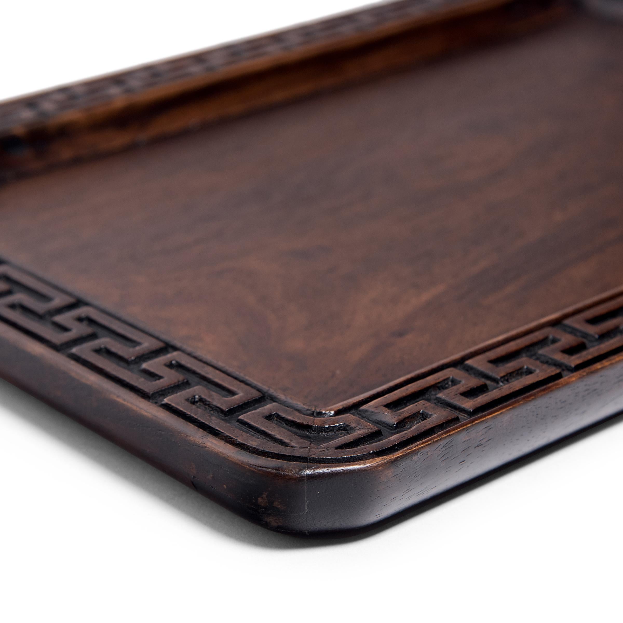 Beautifully carved of a fine-grained hardwood, this late 19th century tray reflects the Qing-dynasty literati's taste for fine materials and balanced proportions. Once used to serve tea or hold scholarly implements, the shallow tray is enclosed in a