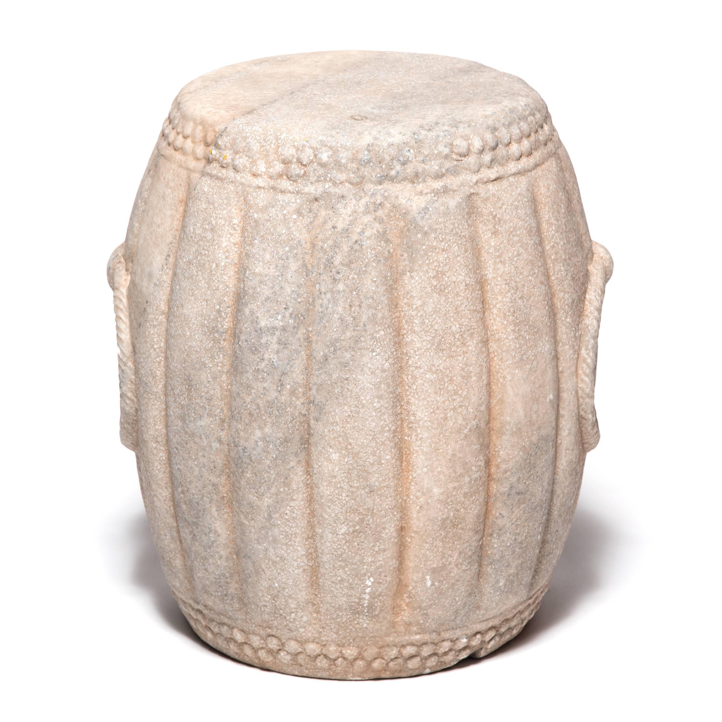 Hand-carved of marble, this drum-shaped stool swells a ribbed melon shape, an ancient symbol of fertility. The artist used a hobnail-like texture on either end to suggest the rivets that fastened the drum's stretched skin head and included