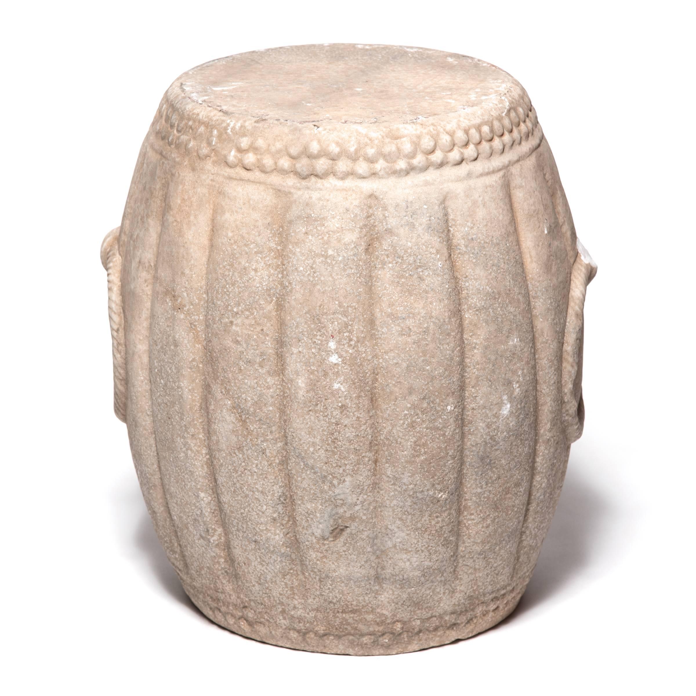 Hand-carved of marble, this drum-shaped stool swells a ribbed melon shape, an ancient symbol of fertility. The artist used a hobnail-like texture on either end to suggest the rivets that fastened the drum's stretched skin head and included