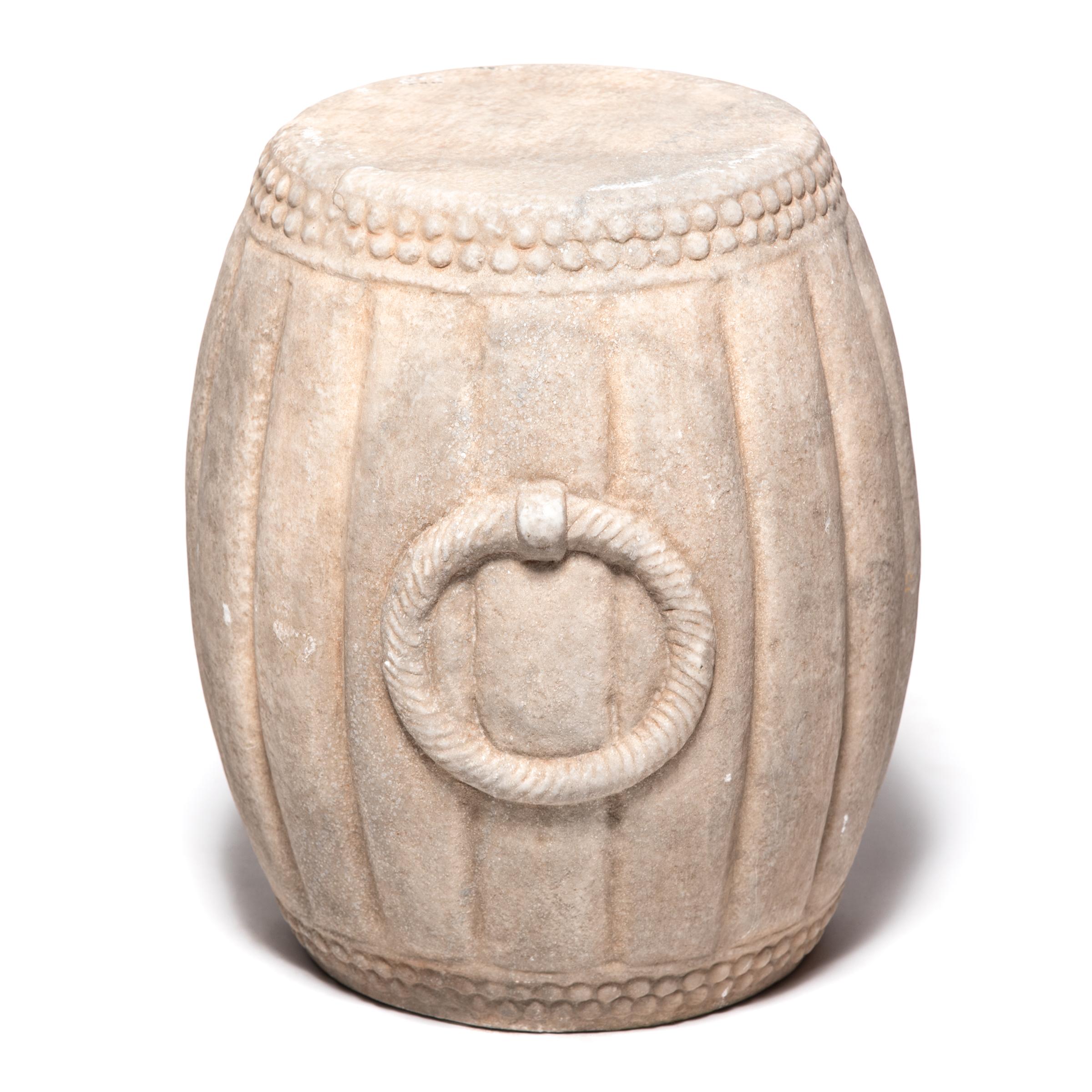 Hand carved of marble, this drum-shaped stool swells a ribbed melon shape, an ancient symbol of fertility. The artist used a hobnail-like texture on either end to suggest the rivets that fastened the drum's stretched skin head and included