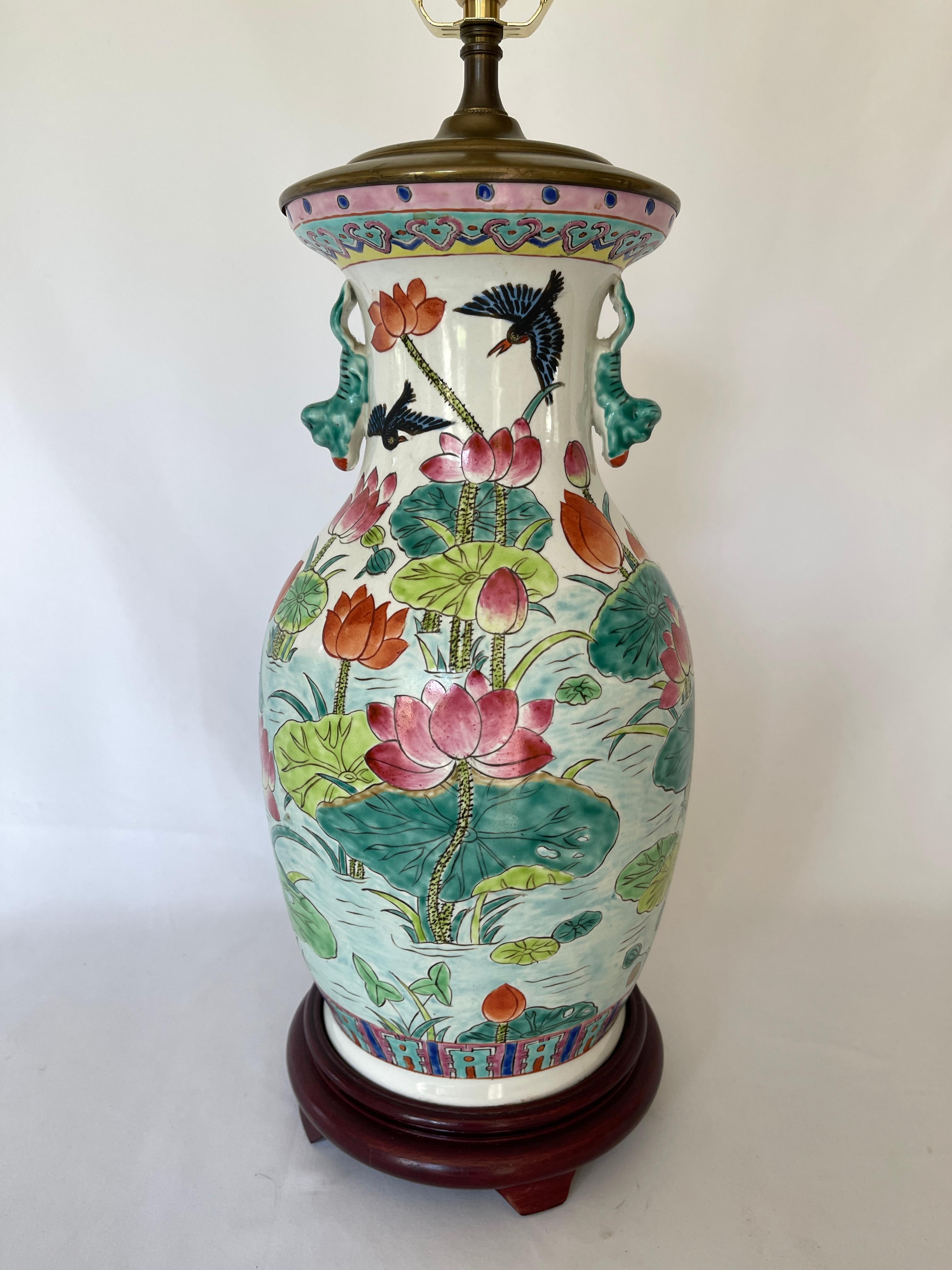 Chinese mid 20th century porcelain baluster vase lamp hand painted with lotus flowers all around. Circular hardwood base with tripod base.
Brass lamp cap and hardware. Lamp has two switches, one on cord and one at socket.
Lamp measures: 34