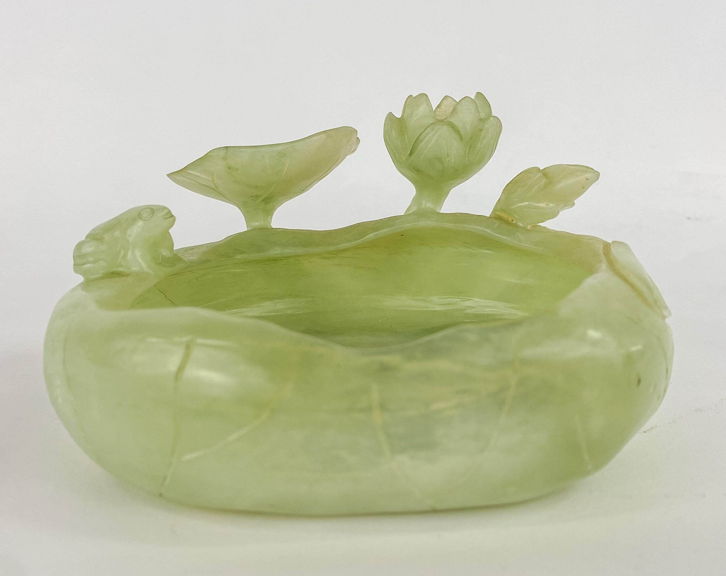 A rare mid century Chinese natural jade bowl. The beautiful green decorative bowl is finely carved and features amazing details of flourishing lotus flowers, one of the most common flowers in China, in different stages. 
This decorative jade bowl
