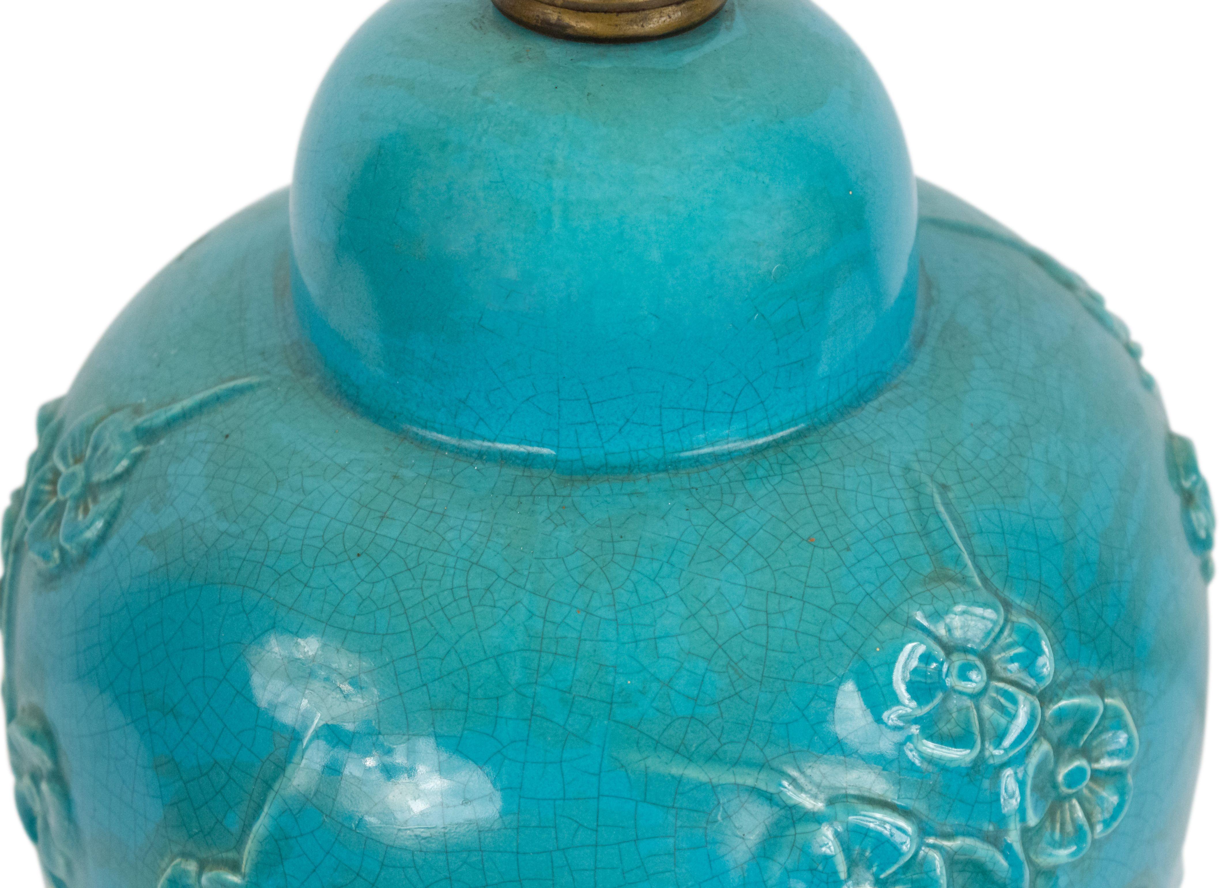 Asian Chinese midcentury turquoise porcelain ginger jar shaped lamp with a floral design in relief and resting on a metal round base.