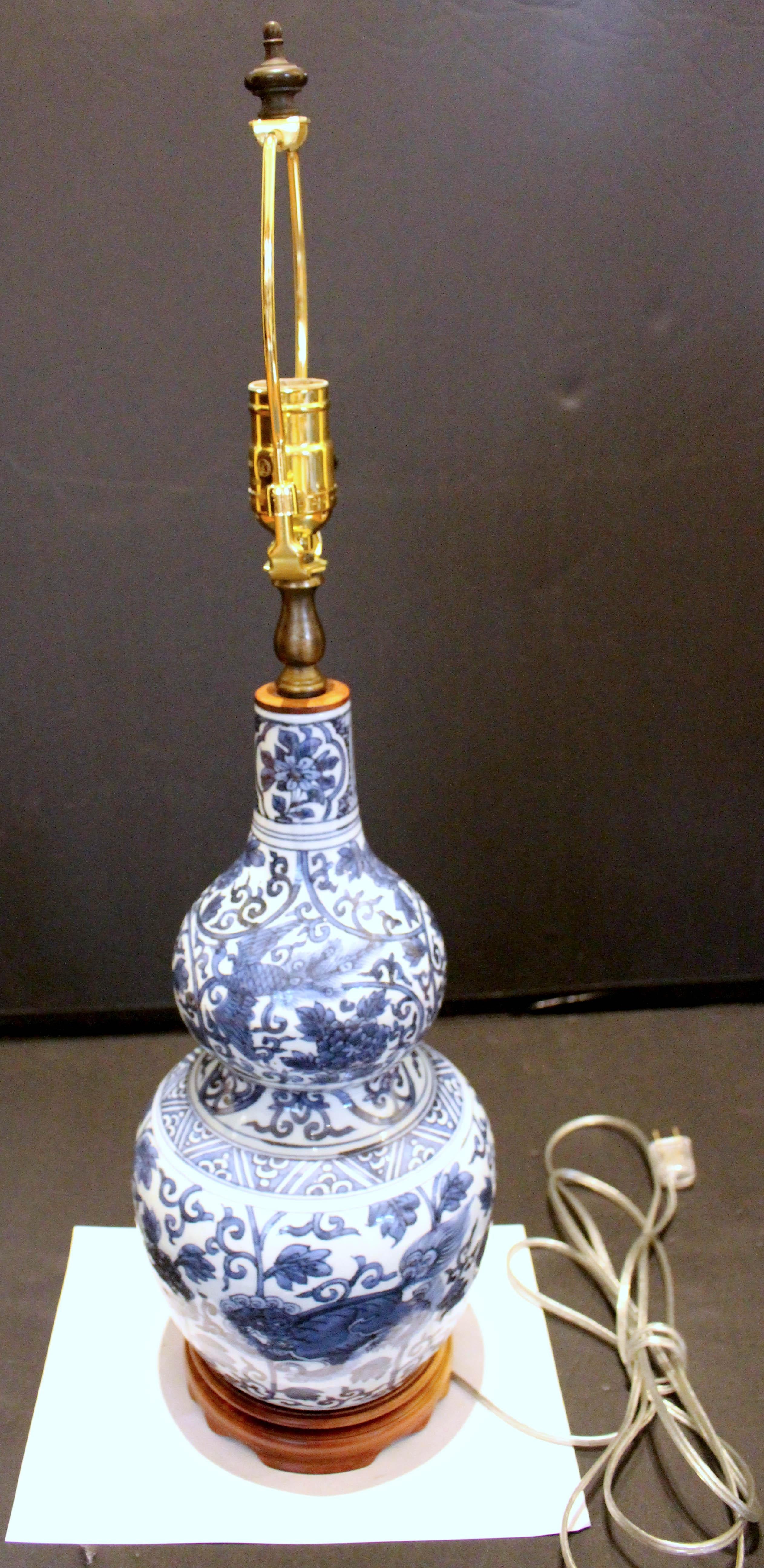 Lampe chinoise à vase bleu et blanc du milieu de la fin du 19e siècle. Vase en forme de gourde en porcelaine très bien décoré d'un grand dragon, d'un chien foo et d'un sanglier, ainsi que d'oiseaux phénix et de pivoines. Vase en bois sculpté avec