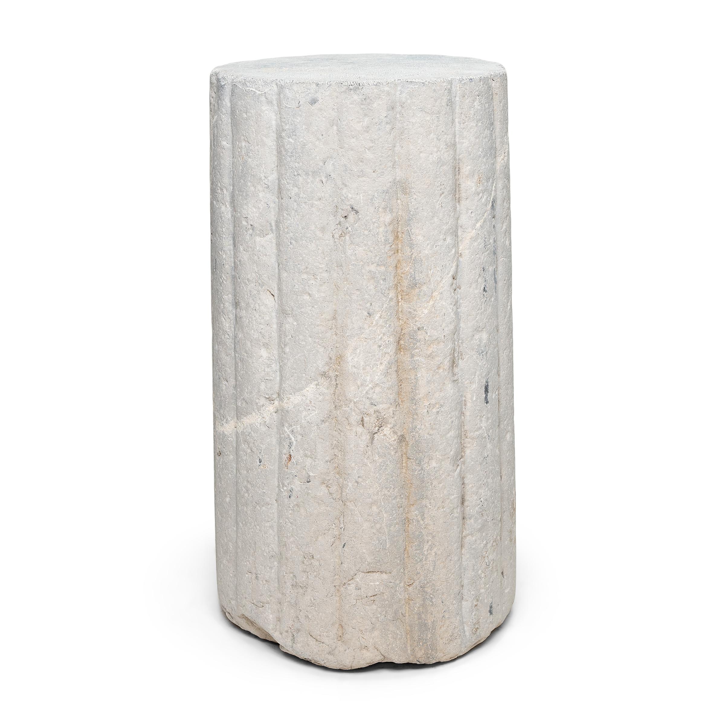 This unusual stone pedestal is actually a late 19th-century cylindrical mill stone. Hand-carved of solid limestone with a textured and ribbed surface, the stone was used for threshing wheat and other grains on a farm in China's Shanxi province. The