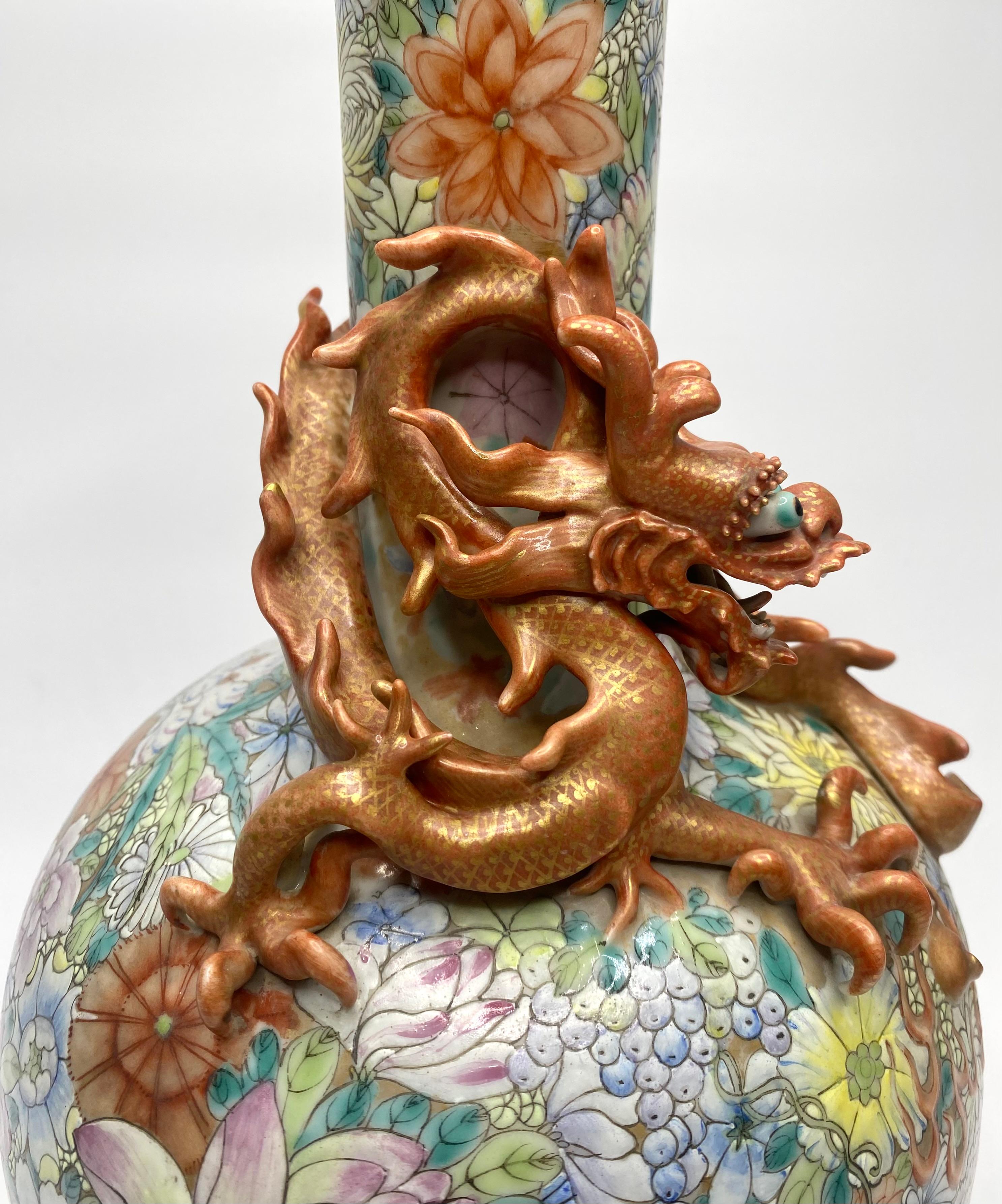 Chinese porcelain ‘Millefleur’ Dragon vase, Republic Period. The bottle shaped vase, well painted in vibrant famille rose enamels, with a profusion of flowers on a gilt ground.
The neck applied with a large, sinuous dragon, chasing a flaming pearl,