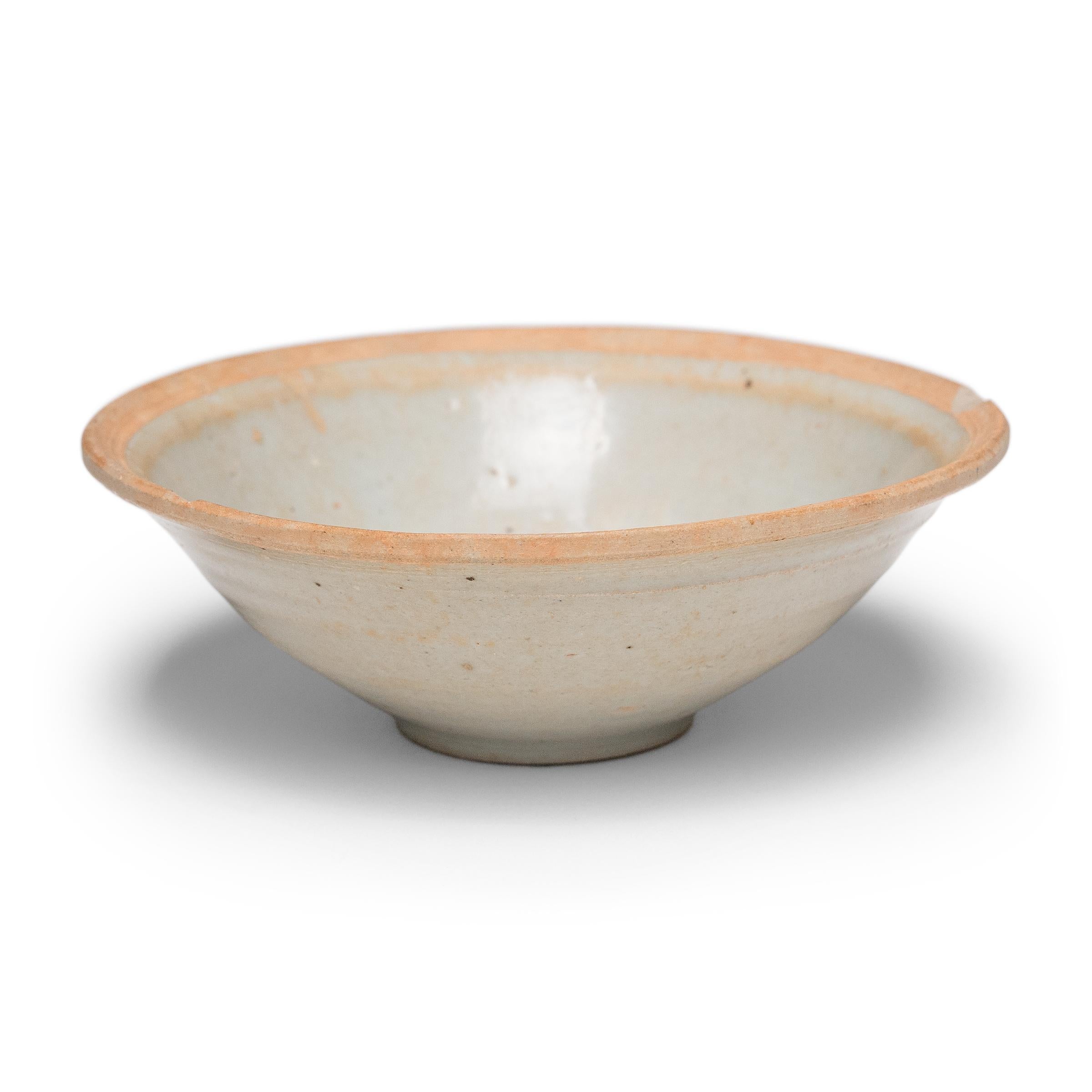 Ce bol en faïence du début de la dynastie Ming (1368-1644) est recouvert à l'intérieur et à l'extérieur d'une glaçure céladon pâle de couleur bleu clair. Autrefois utilisé quotidiennement pour boire et manger, le bol a des parois minces, un pied peu