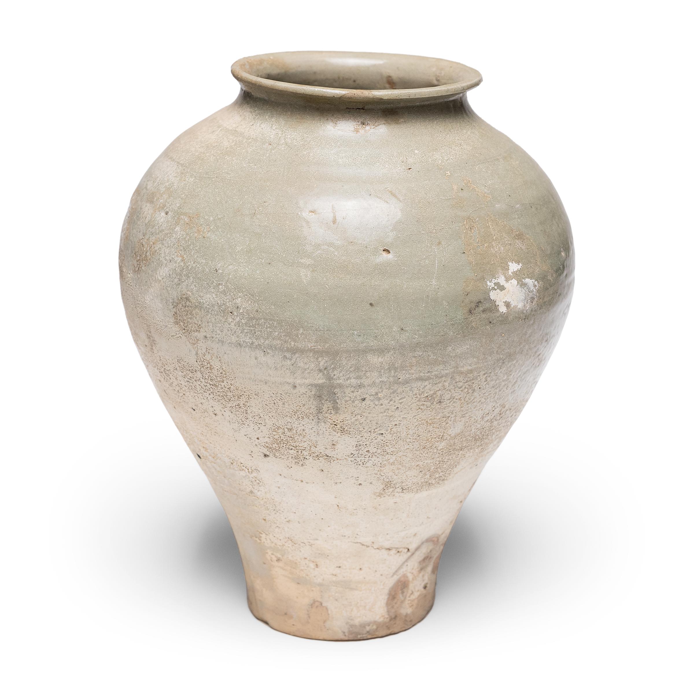 Grâce à la simplicité de sa forme et à sa glaçure brillante, cette jarre du XVIe siècle destinée à contenir de l'alcool de riz ou des spiritueux témoigne du raffinement tranquille de la poterie de la dynastie Ming. La forme en faïence est recouverte