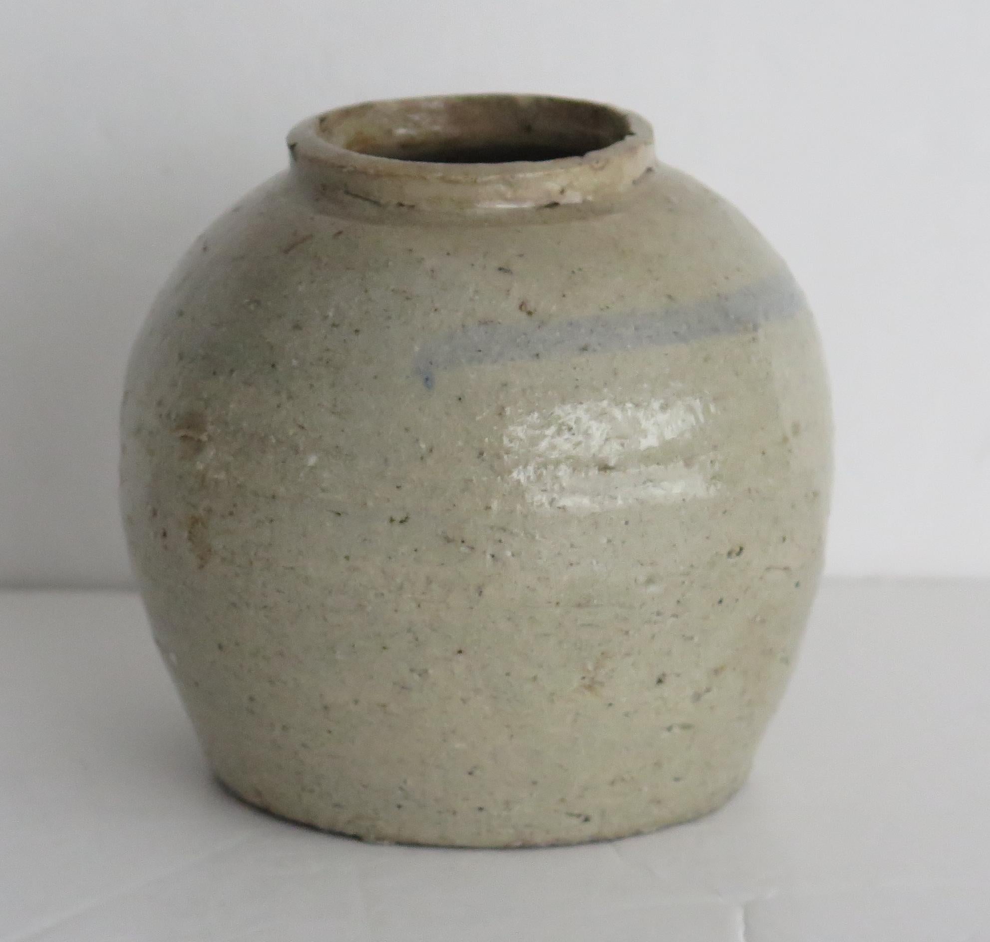 This is a Chinese hand-thrown ceramic provincial jar with a light celadon glaze which we date to the Ming period of the early 17th century or possibly earlier.

The jar is hand potted with a short neck and simply decorated with a ring hand painted