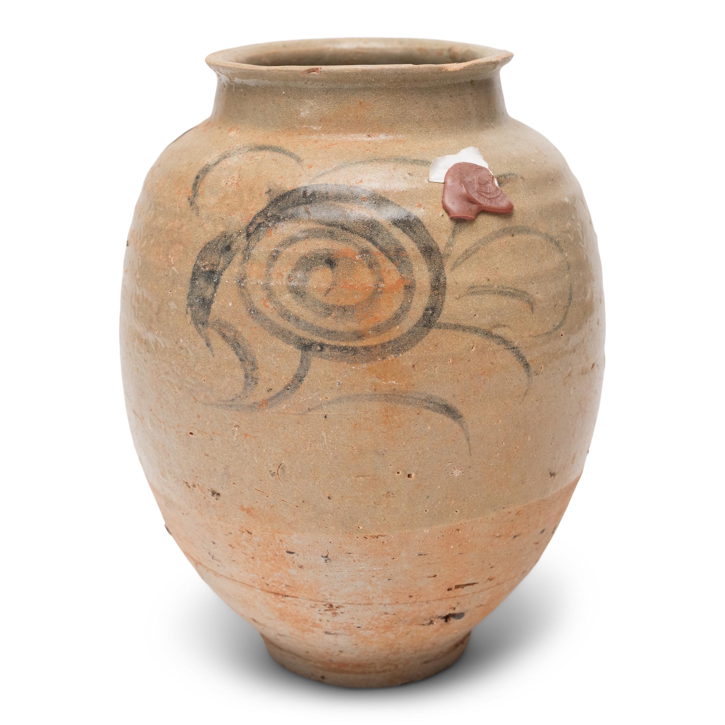 This Ming-dynasty (1368-1644) storage jar is attributed to the kilns of Yunnan province, loosely decorated with cobalt underglaze in a manner typical of the region. Dated to the 15th/16th century, the small jar is potted to an ovoid form with a