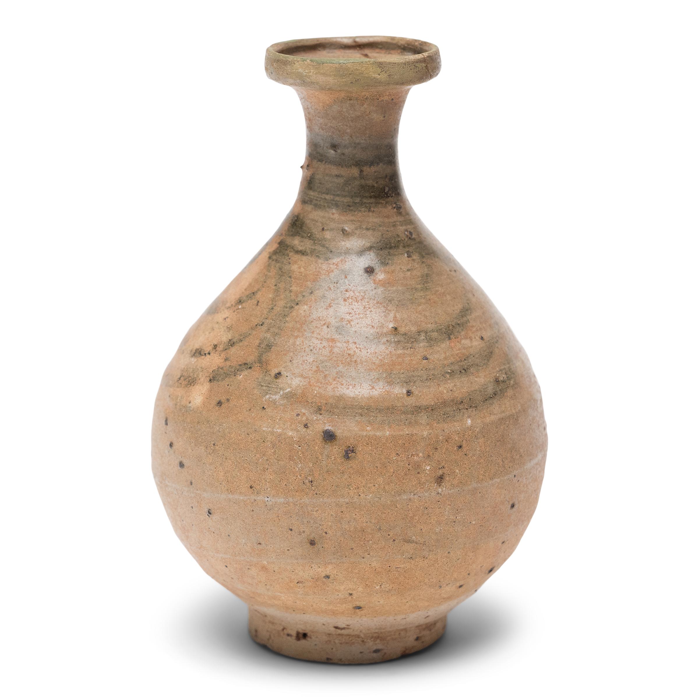This elegant ceramic vessel is a Ming-dynasty (1368-1644) bottle originally used for storing oil or sauces. Dated to the 15th/16th century, the bottle has a gracefully curved form known as yuhuchunping, or pear-shaped vase, and is potted with a