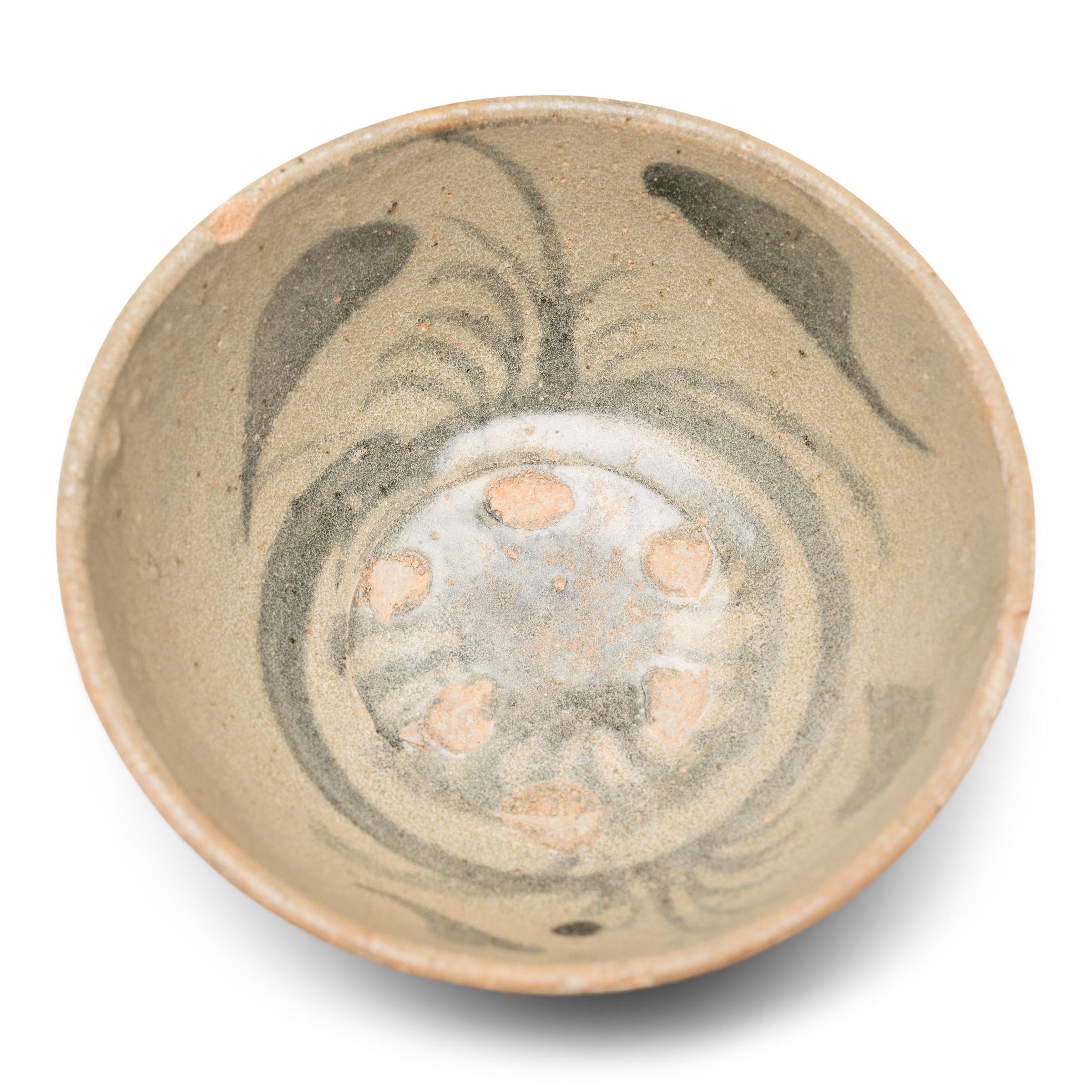 This Ming-dynasty (1368-1644) bowl is attributed to the kilns of Yunnan province, painted in dark cobalt underglaze with floral motifs and sweeping brushstrokes. Dated to the 15th/16th century, the small footed bowl was once used daily for food and