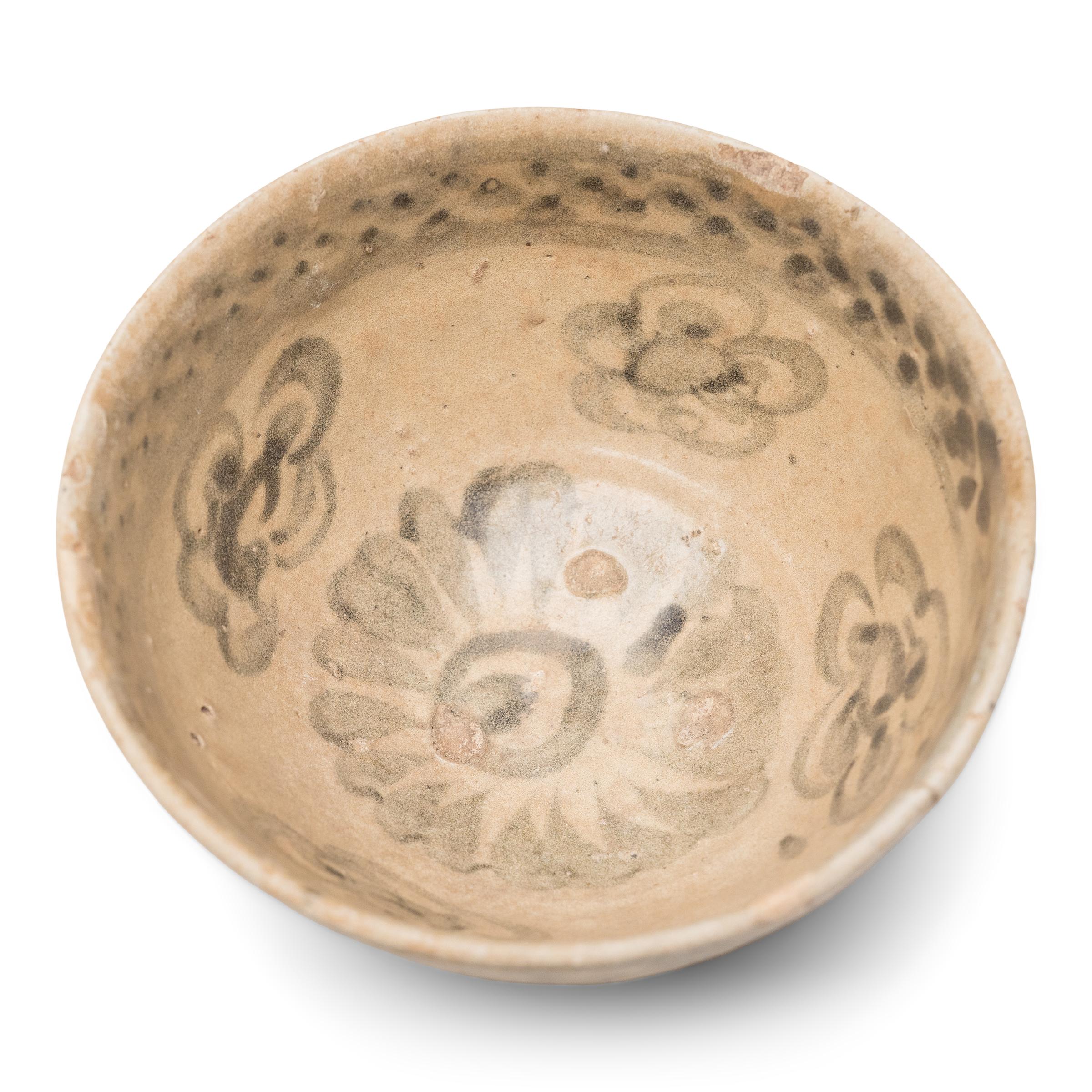 This Ming-dynasty (1368-1644) bowl is attributed to the kilns of Yunnan province, painted in dark cobalt underglaze with flower blossoms and sweeping brushstrokes. Dated to the 15th/16th century, the small footed bowl was once used daily for food
