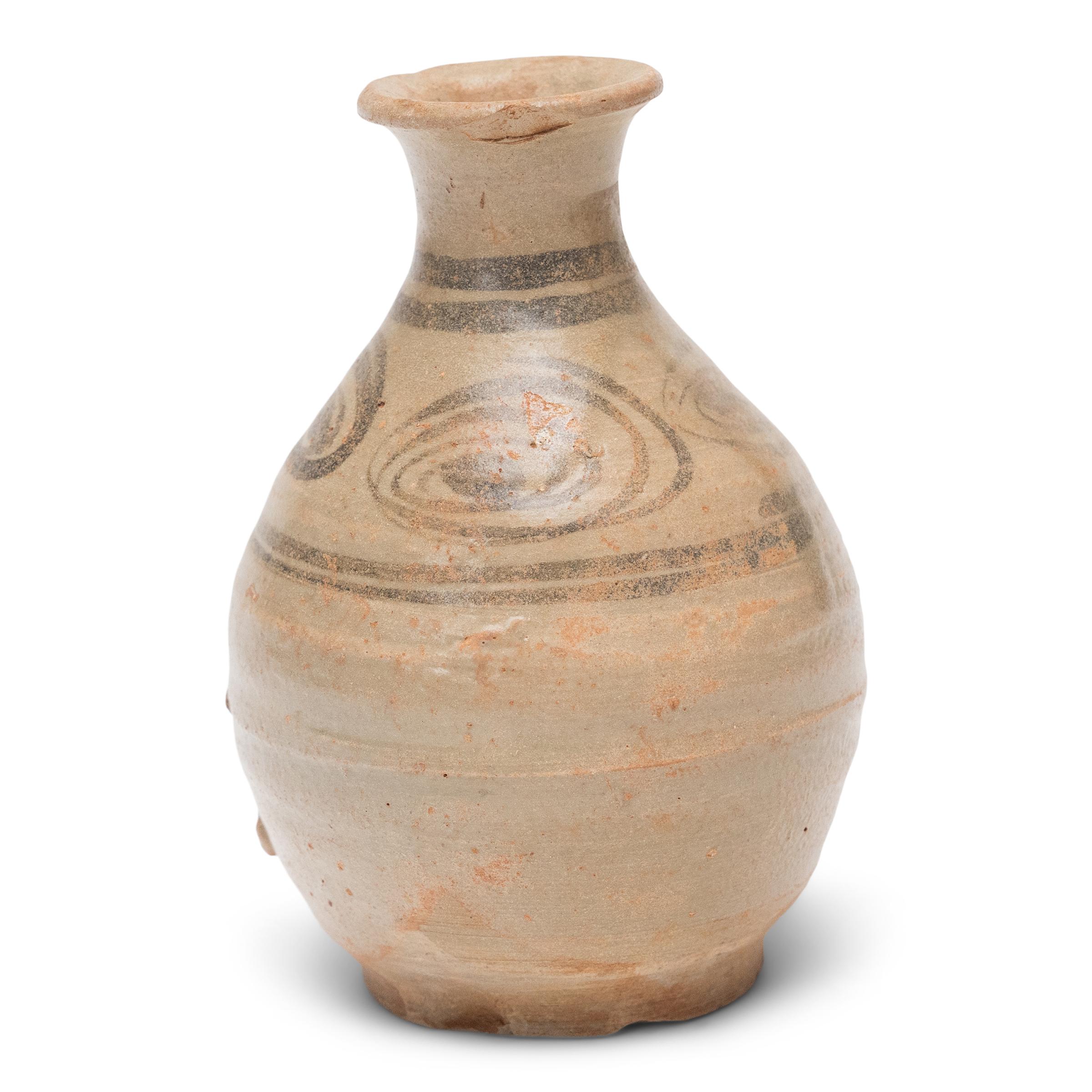 This petite ceramic bottle is a Ming-dynasty (1368-1644) vessel originally used for serving rice wine or spirits. The gracefully curved form is known as a yuhuchunping, or pear-shaped vase, and is defined by its rounded body, tapered neck and flared