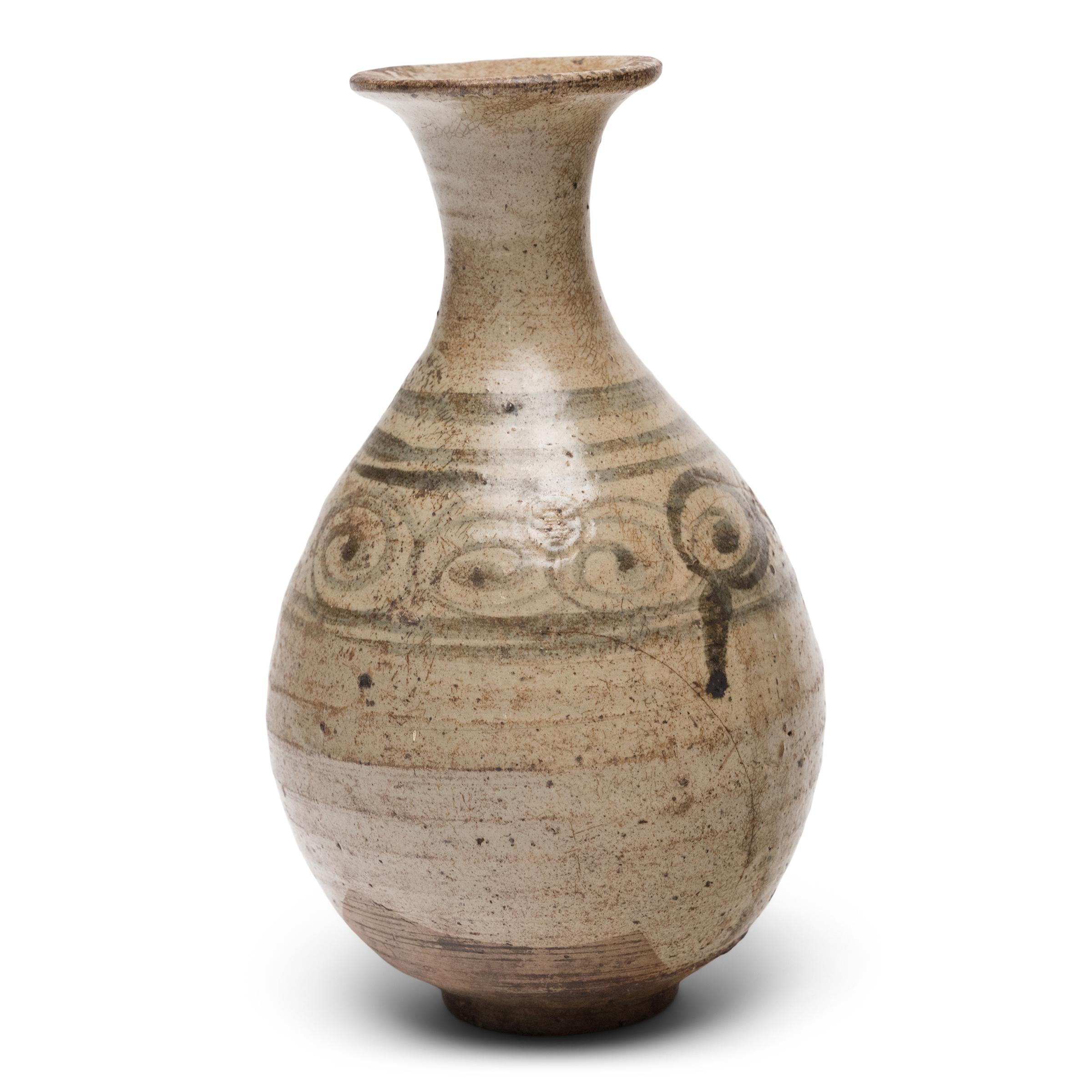 This delicate ceramic bottle is a Ming-dynasty (1368-1644) vessel originally used for serving rice wine or spirits. The gracefully curved form is known as a yuhuchunping, or pear-shaped vase, and is defined by its rounded body, tapered neck and