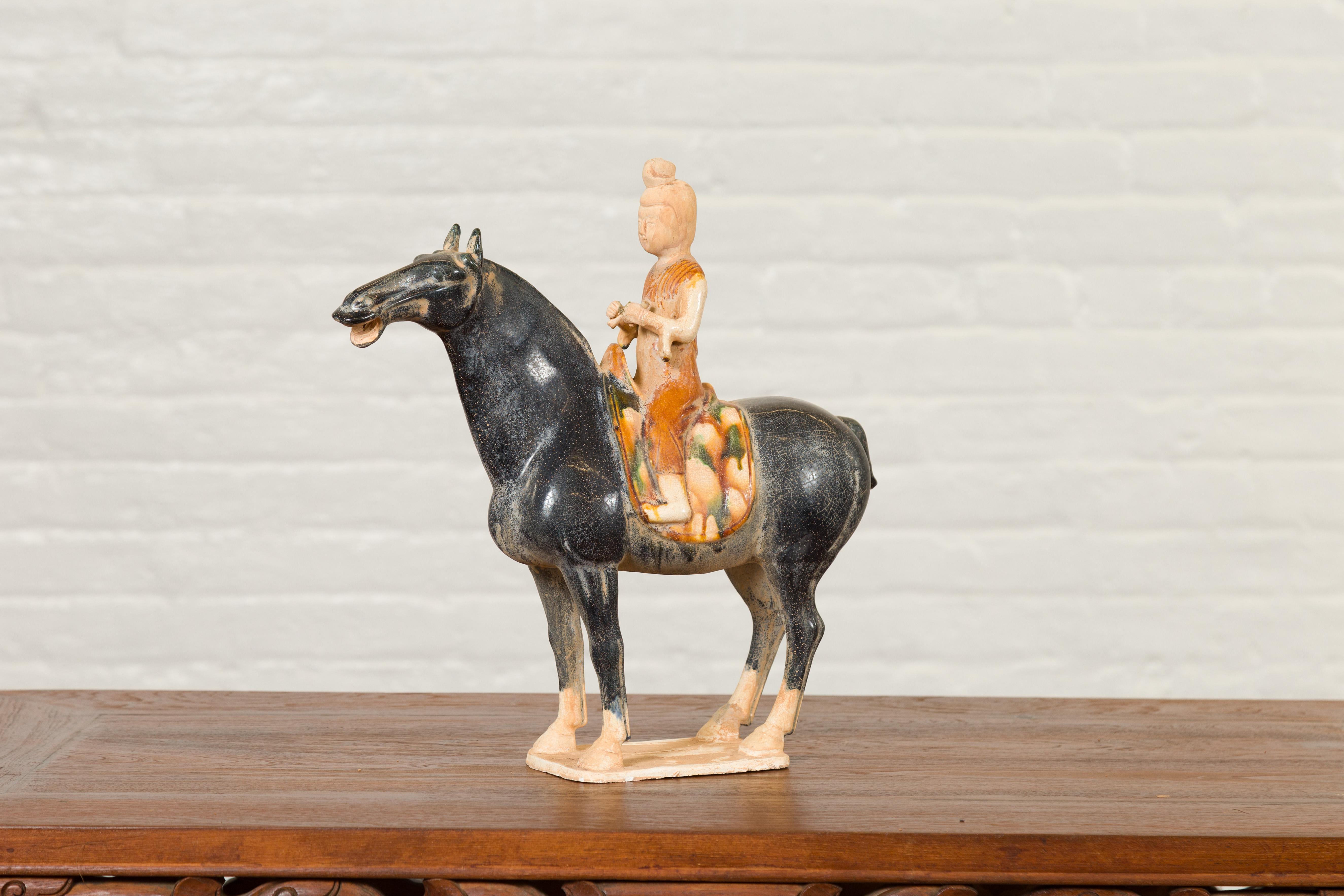 A Chinese Ming dynasty style glazed terracotta horse and rider sculpture from the 20th century with polychrome finish. Crafted in the Ming style, this small terracotta horse and rider attracts our attention with its tricolor glazed finish. A rider