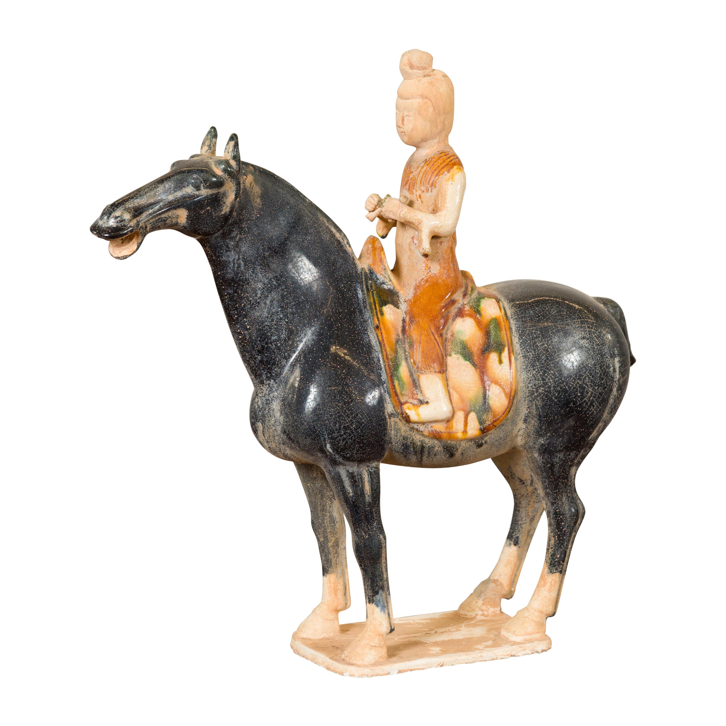 A Chinese Ming dynasty style glazed terracotta horse and rider sculpture from the 20th century with polychrome finish. Crafted in the Ming style, this small terracotta horse and rider attracts our attention with its tricolor glazed finish. A rider