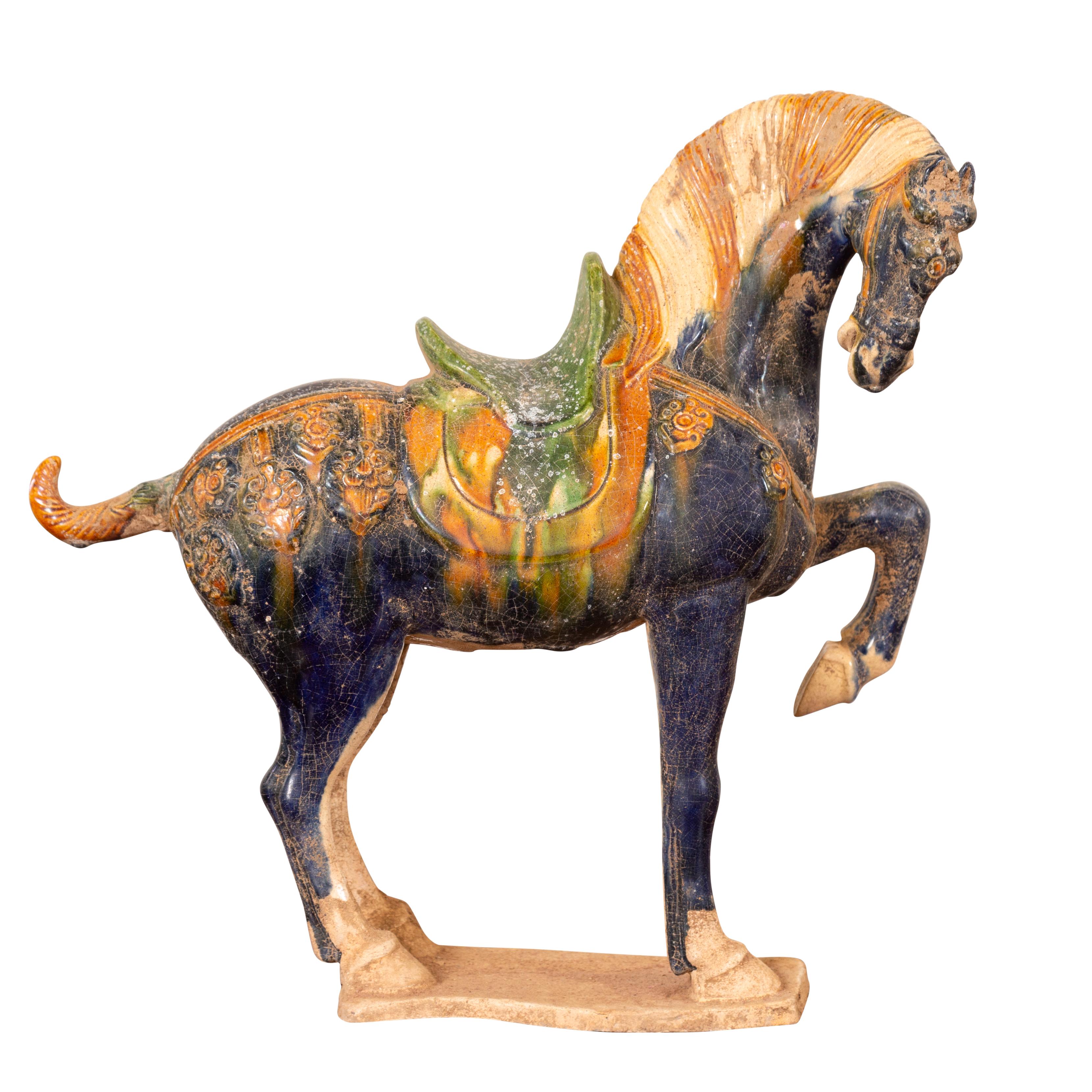 A Chinese Ming dynasty style glazed terracotta prancing horse figure from the 20th century with polychrome finish. Crafted in the Ming style, this small terracotta prancing horse attracts our attention with its graceful stance and tricolor glazed