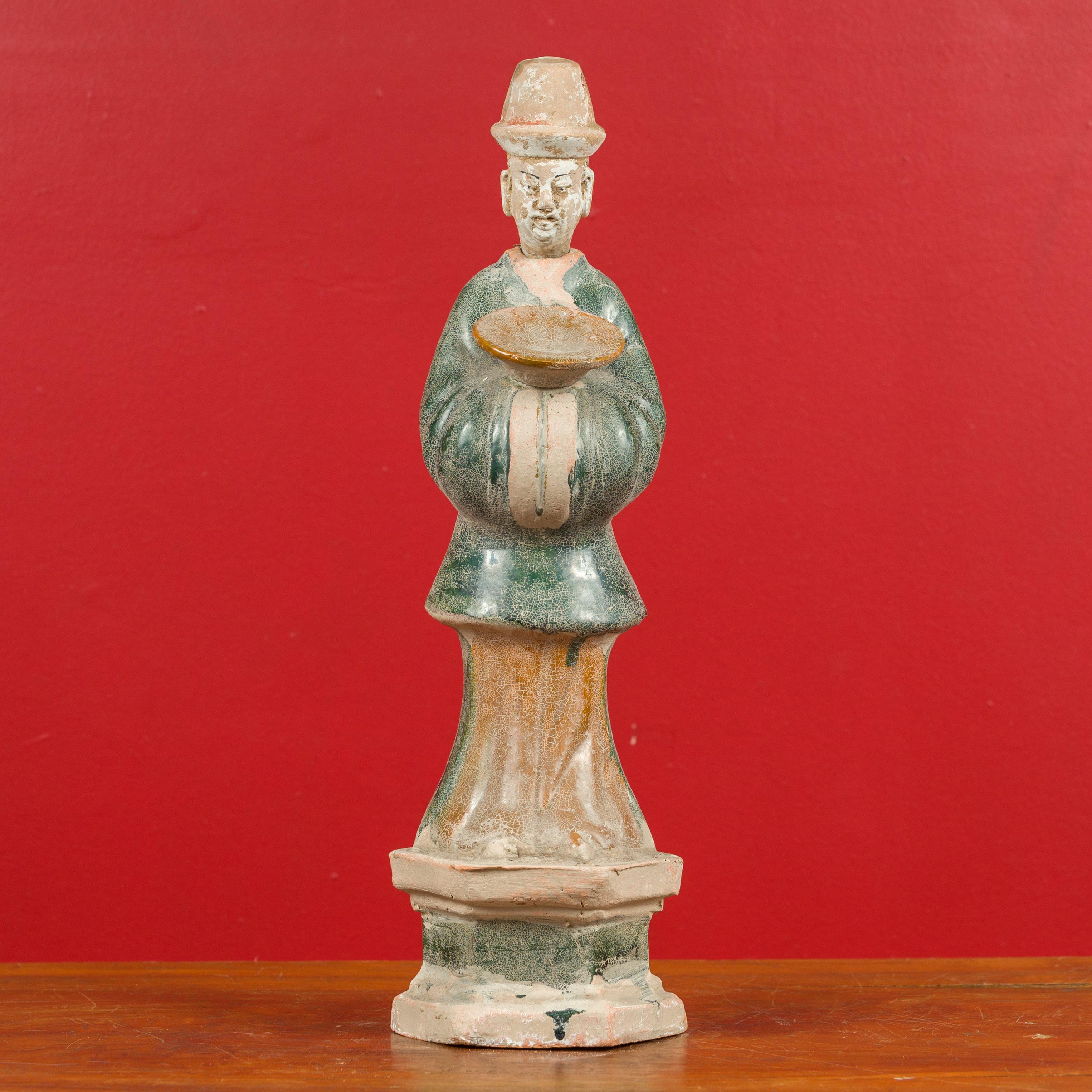 A petite antique Chinese Ming dynasty period glazed terracotta statue from the 17th century, depicting an official holding a bowl. Presenting a nice patina, this Ming Dynasty statue attracts our attention with its green, russet, black and white