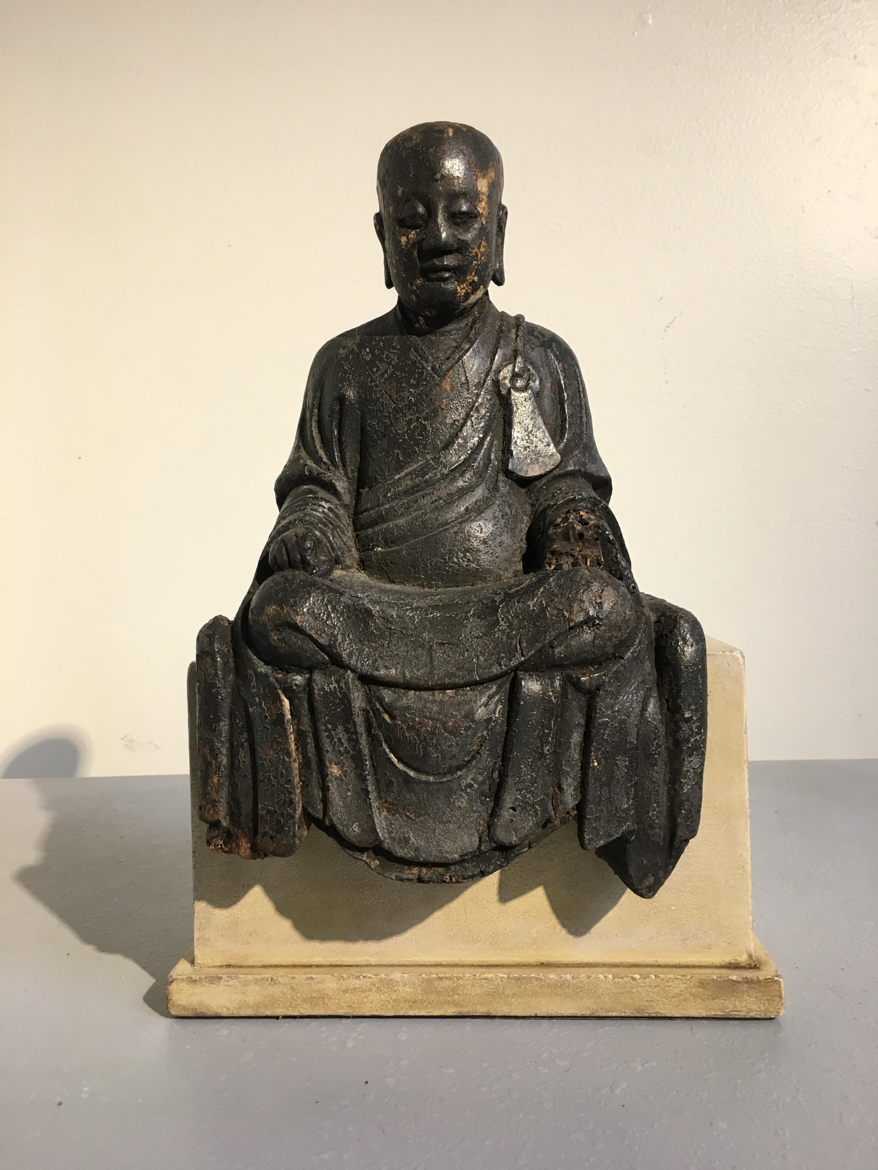 A serene and charming Chinese carved and lacquered wooden figure of an Arhat or Luohan, late Ming dynasty, circa 1600.
The noble figure depicts and elderly disciple of the Buddha, known as a Luohan or Arhat. He is portrayed seated upon a platform