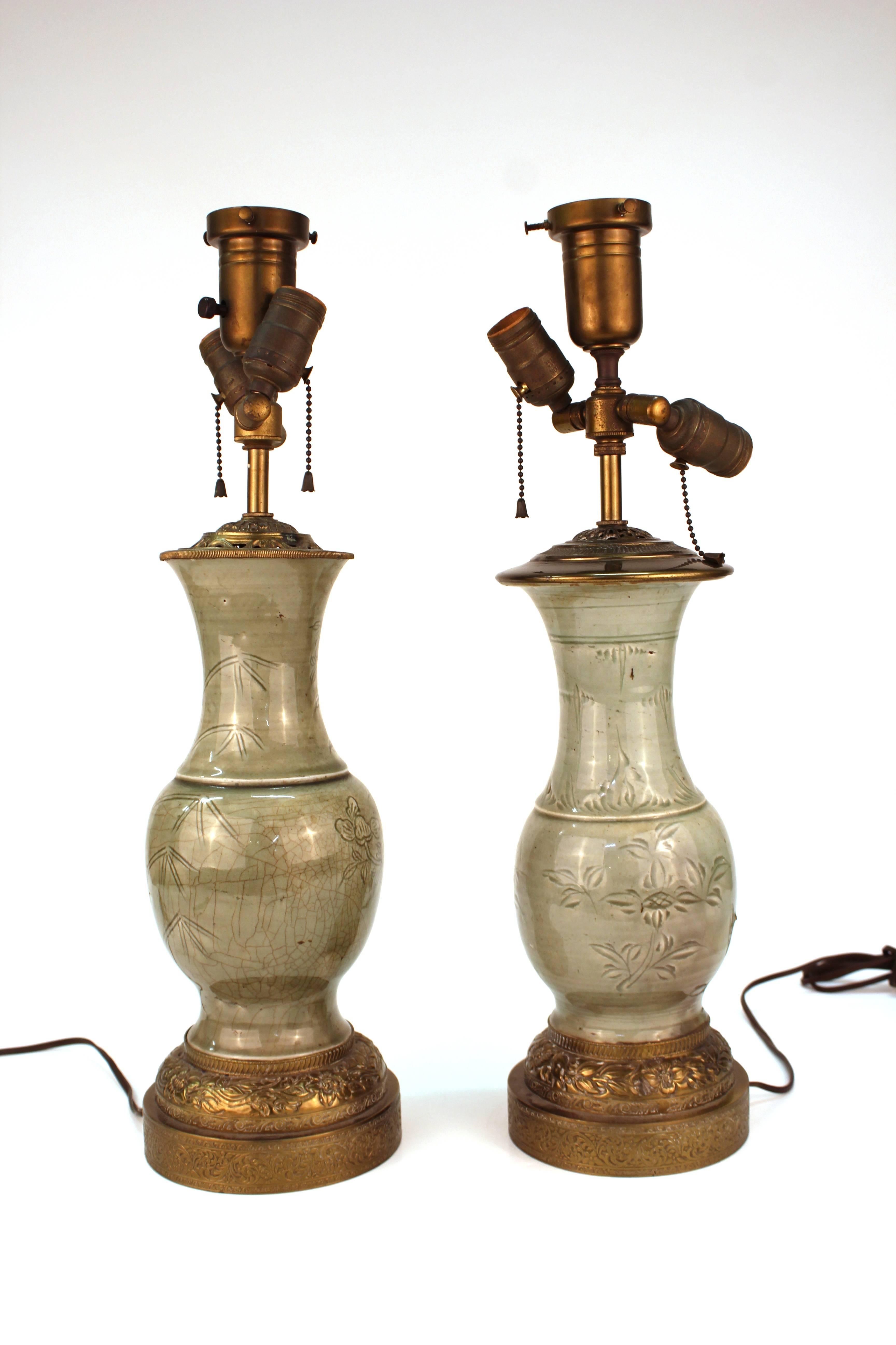 Pair of Chinese Ming dynasty Longquan table lamps in celadon glazed porcelain in the shape of yen yen vases with gilt brass fittings and a bamboo and flowering vines motif. The pair is in good antique condition.