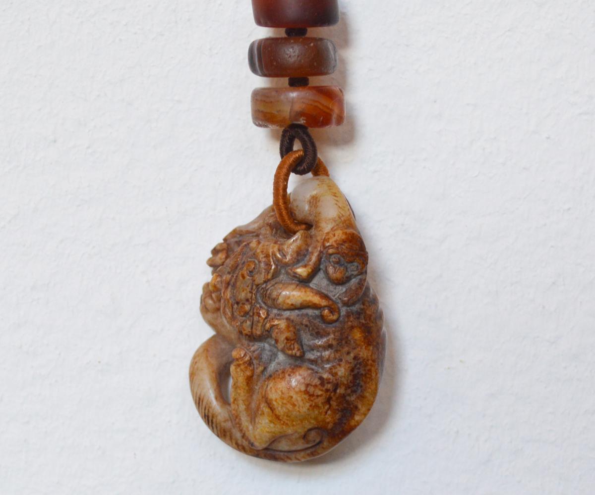 This fine Chinese Ming dynasty jade monkey of rust color has been well preserved and is presented on a more recent but still old necklace for display. Both jade and monkeys carry great importance in the Chinese culture. Jade is a symbol of serenity